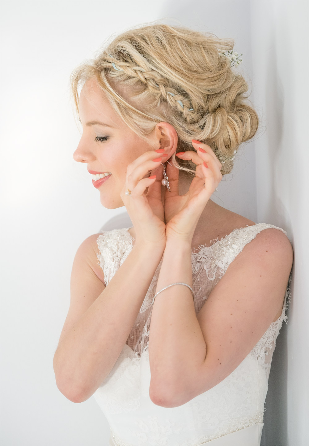 Heidi fastening an earring by the window before her Southend Barns wedding