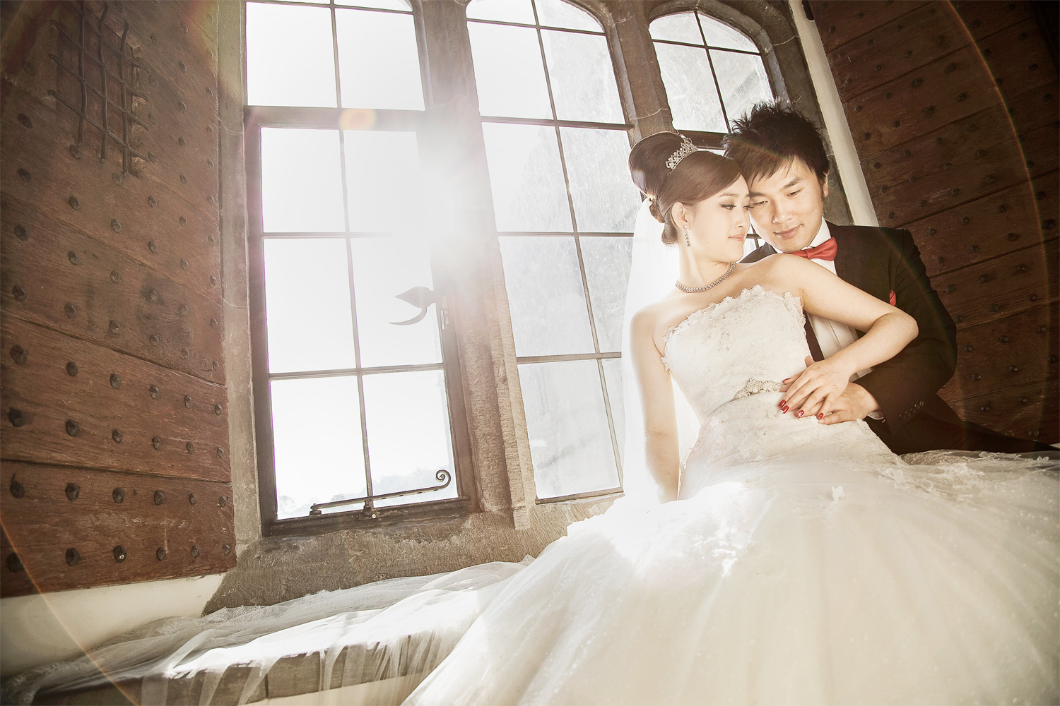 Bride and groom sitting in a deep castle window flooded with light at Leeds Castle