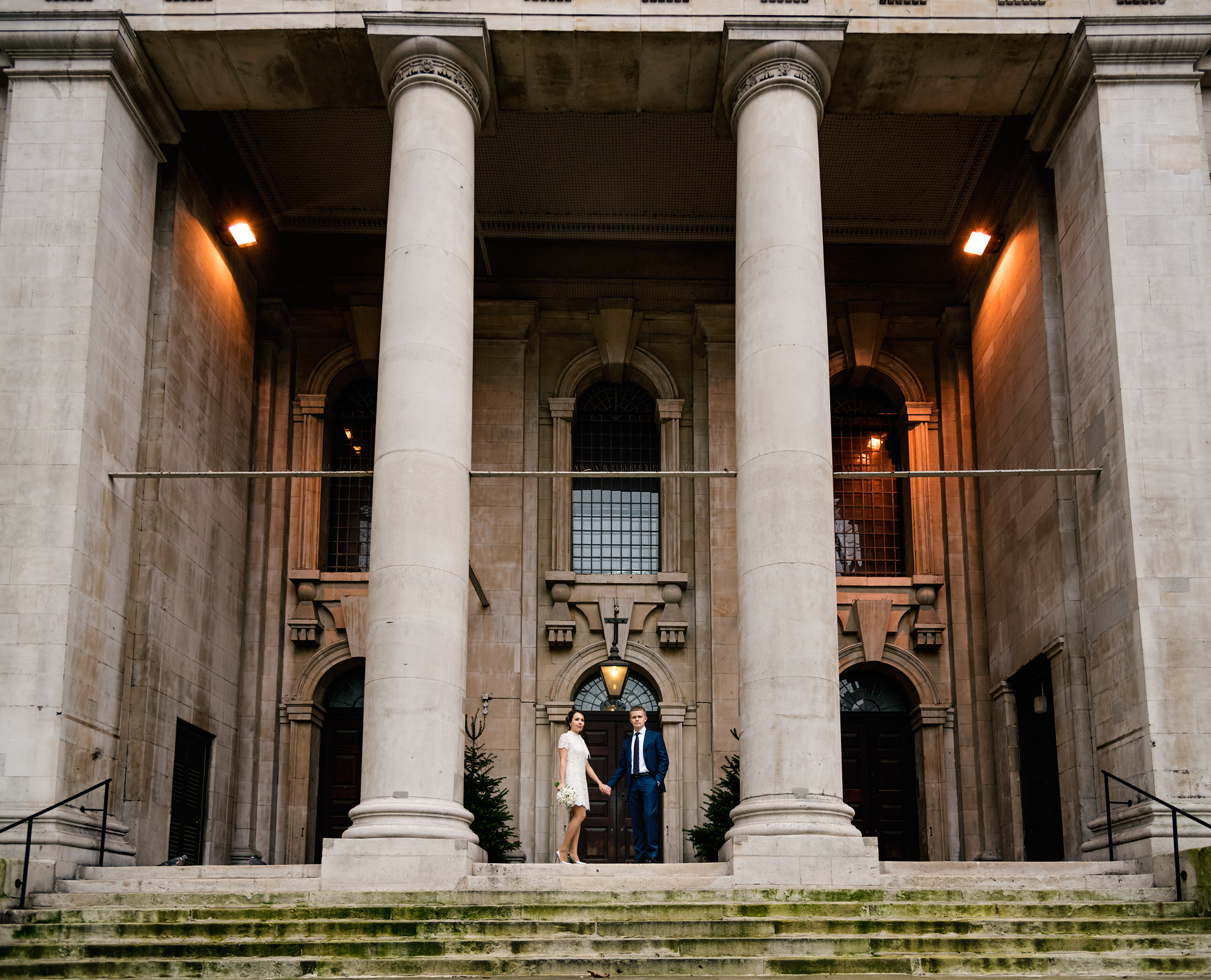 Bride and groom under a stone archway near Chelsea Old Town Hall