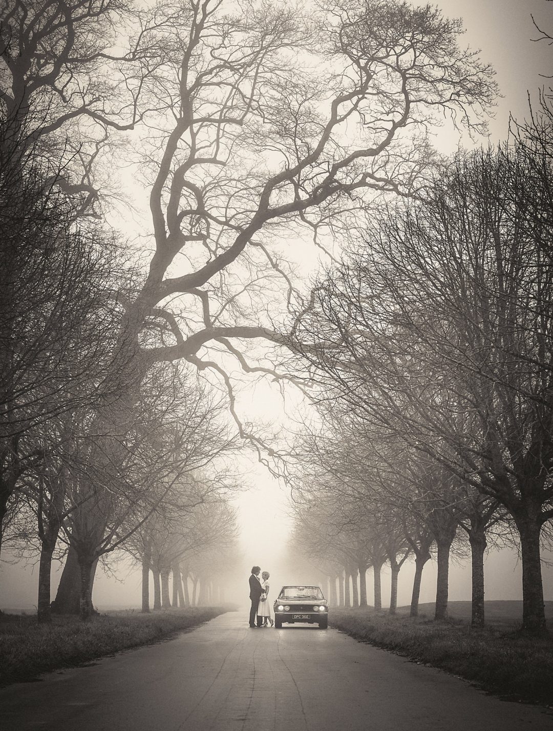 Couple on a misty tree-lined drive near the Kennels at Goodwood