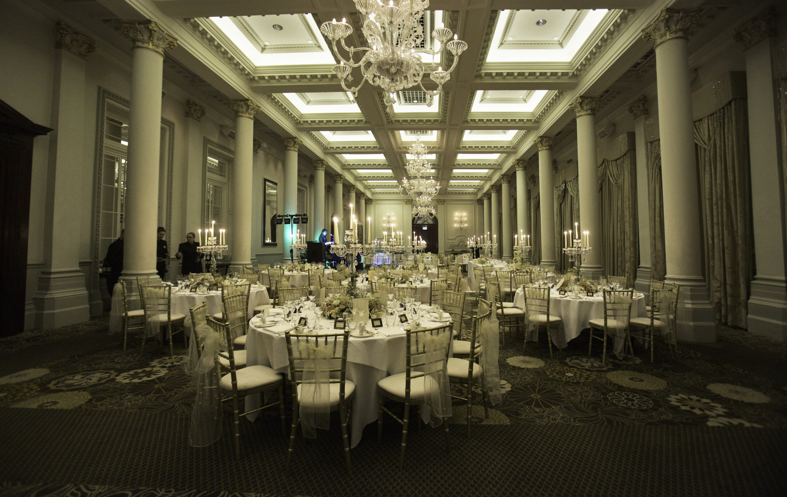 Tables set for a wedding dinner beneath chandeliers at The Langham, London