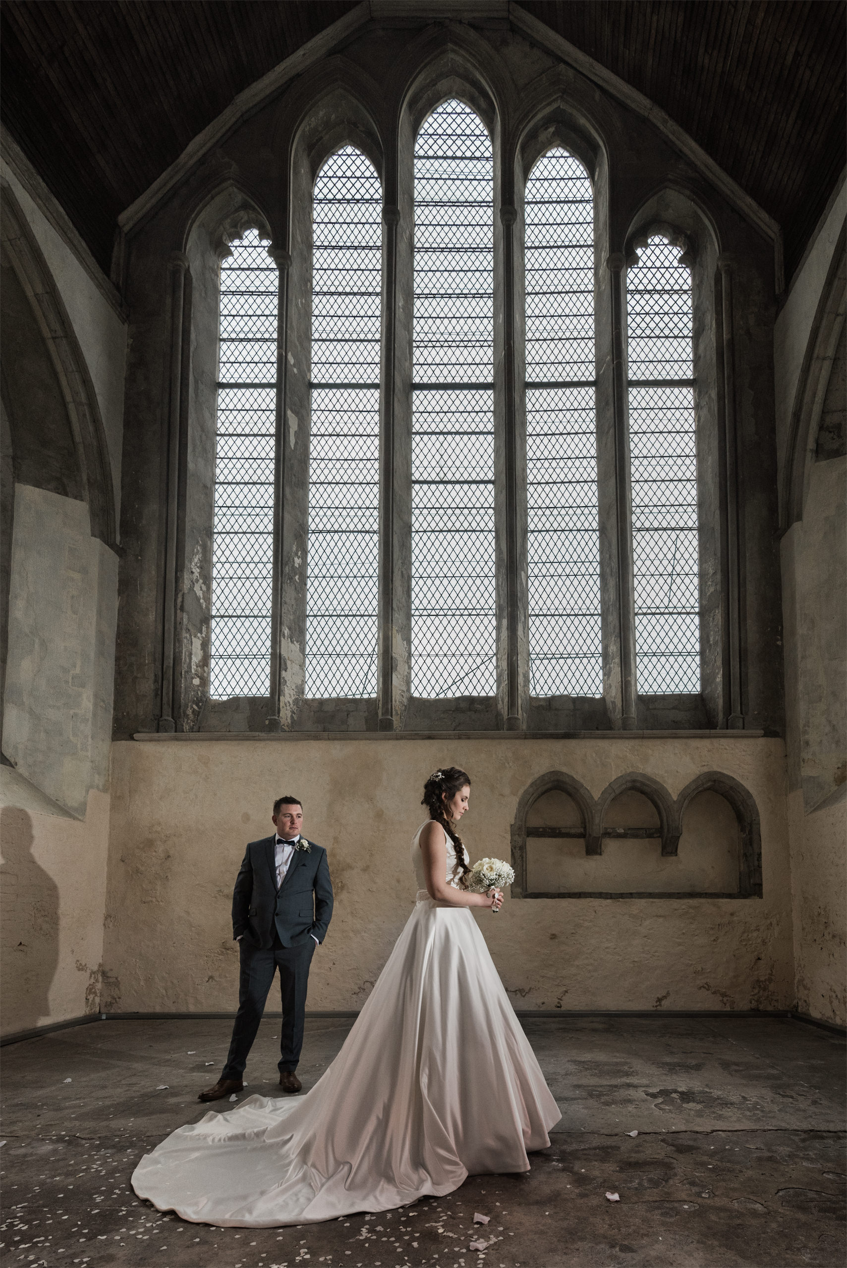 Bride and groom beneath the tall windows inside Chichester Guildhall