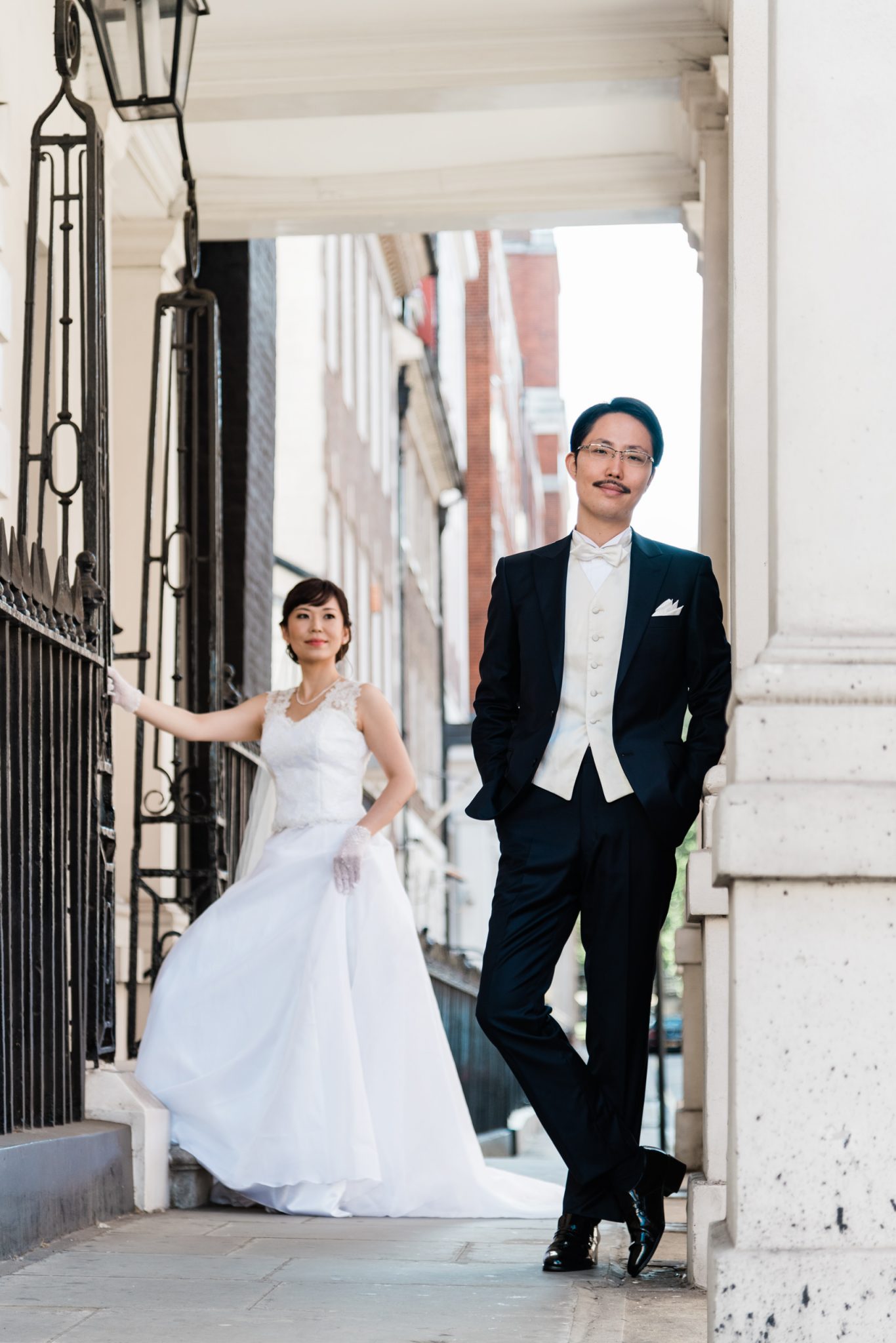 Bride and groom standing in a white Mayfair doorway beside a black lantern