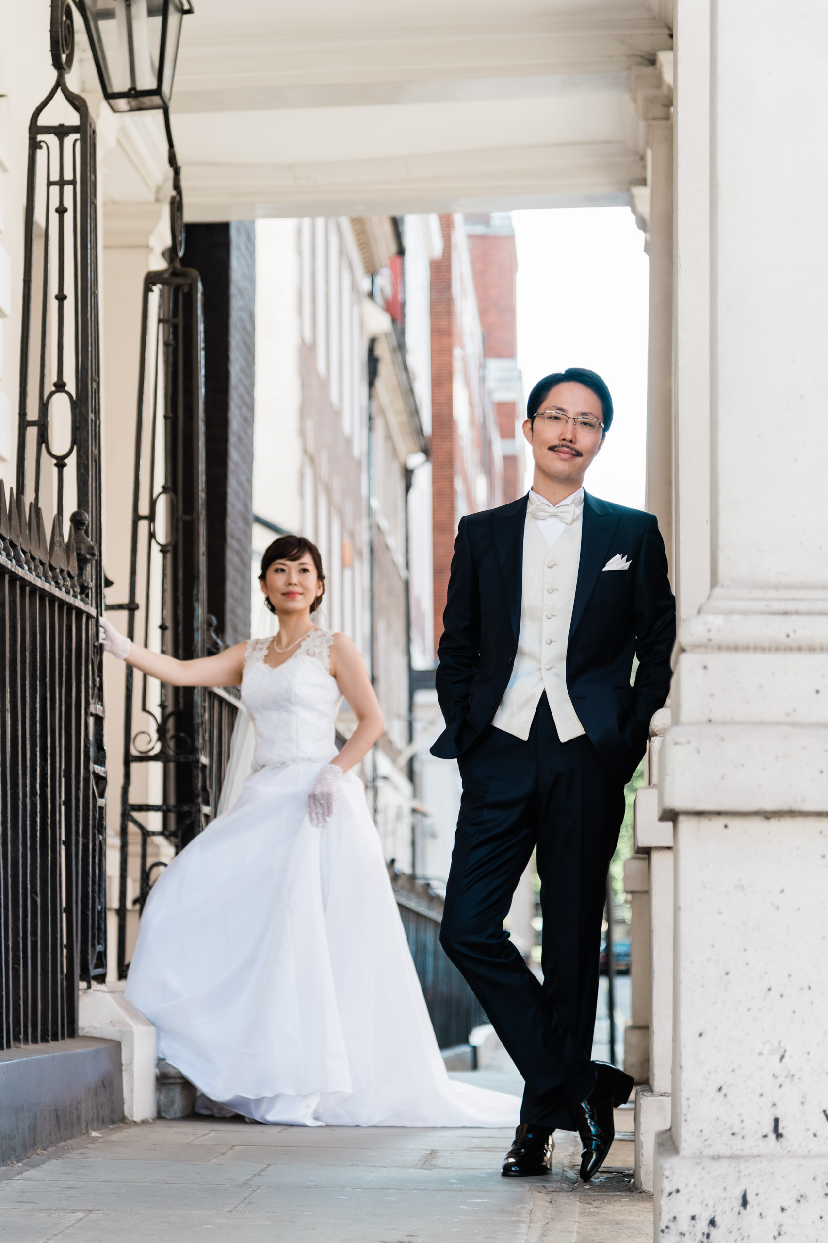 Bride and groom under a stone portico on a Mayfair street in London