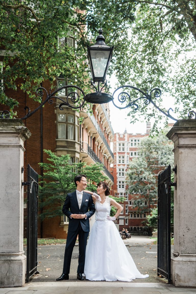 Japanese couple on a London pre wedding photoshoot beneath a tree beside a red brick building