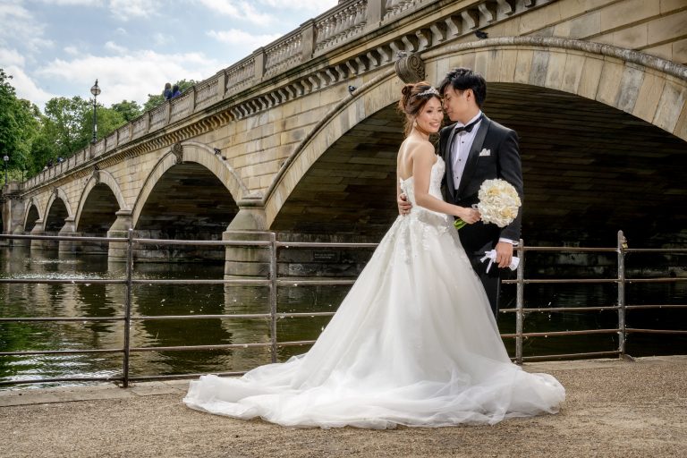 Bride and groom by a stone bridge over the Serpentine in Hyde Park