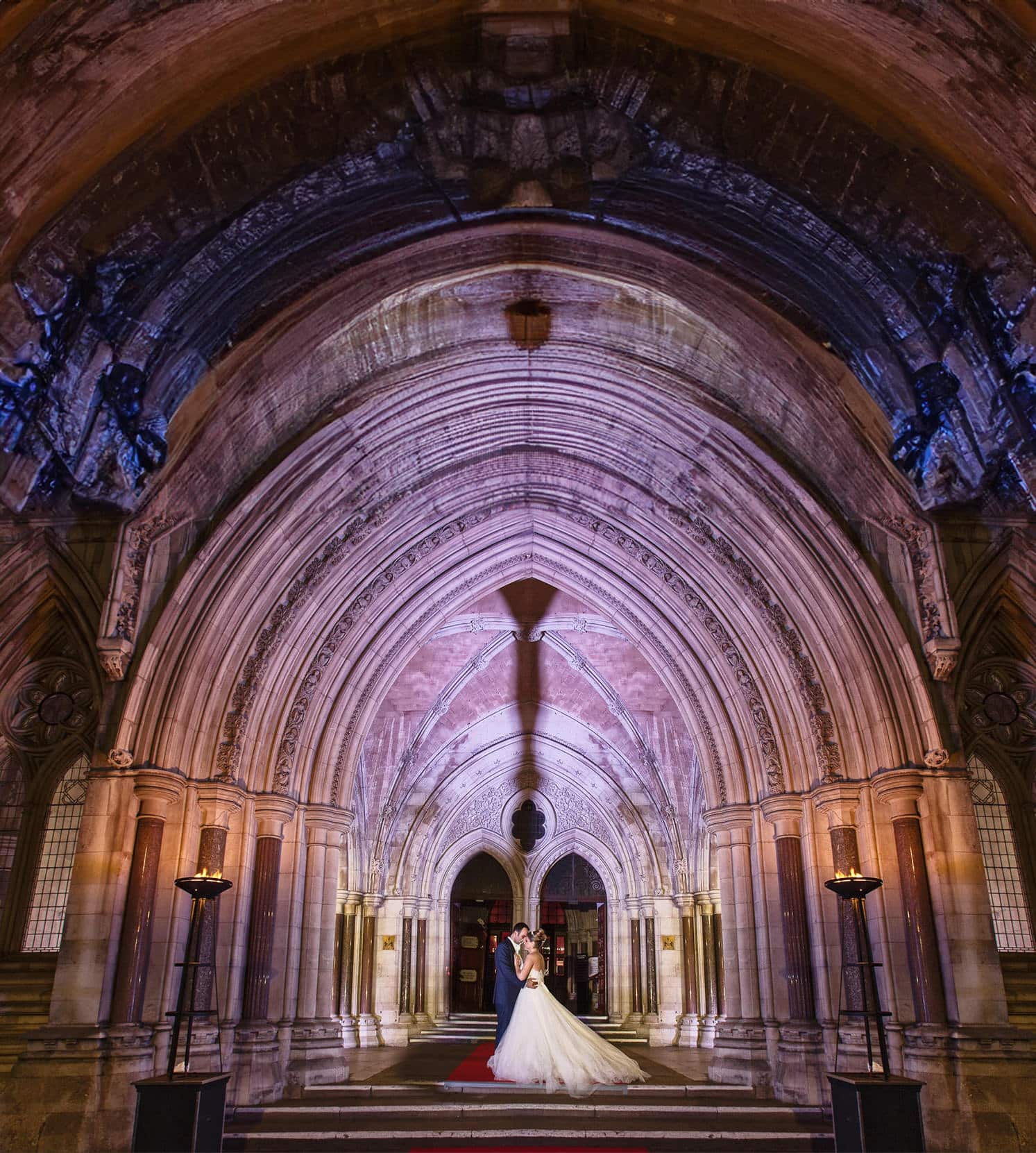 Bride and groom under the lit Gothic arches of the Royal Courts of Justice, London