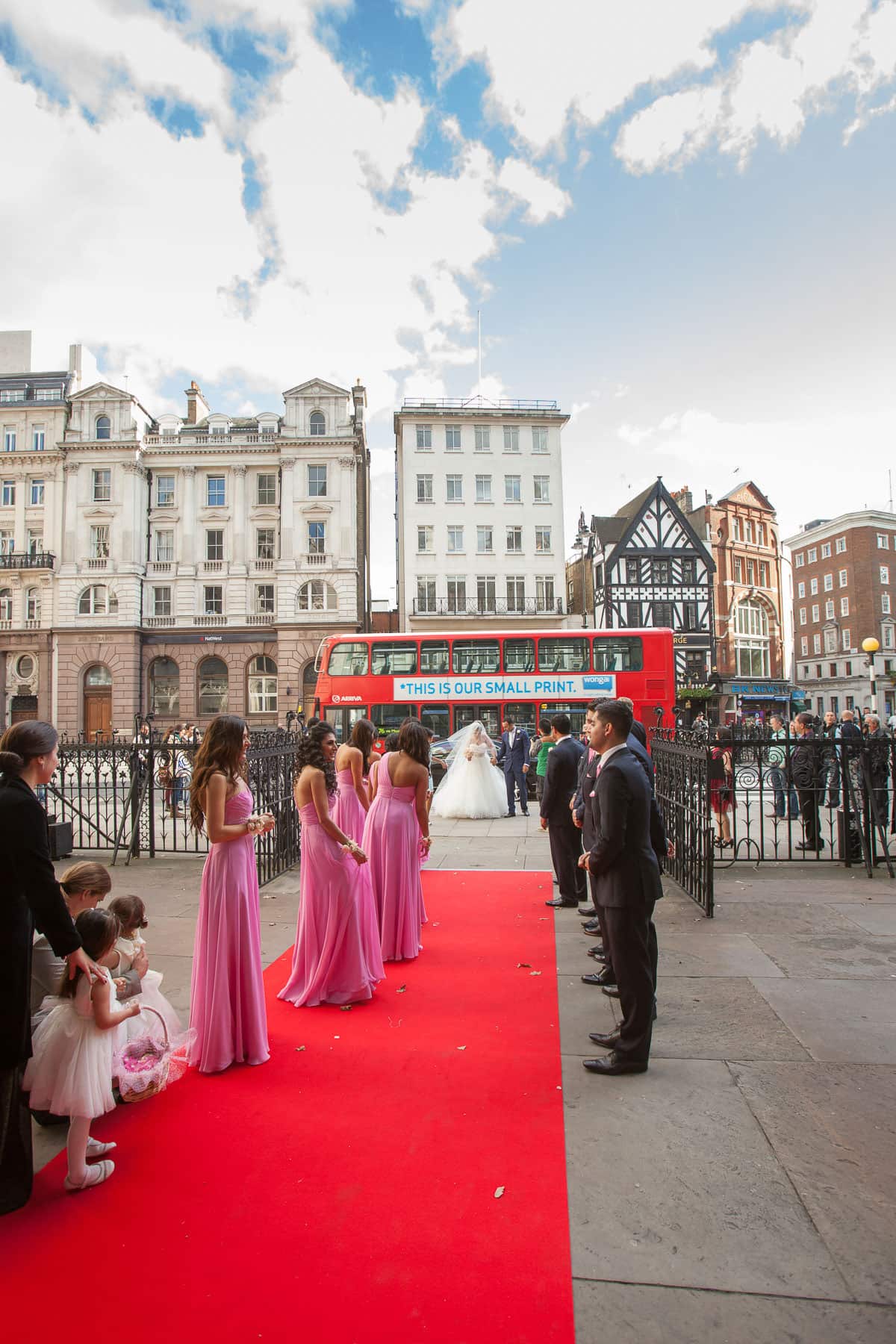 Bridesmaids in pink lining a red carpet outside the Royal Courts of Justice in London