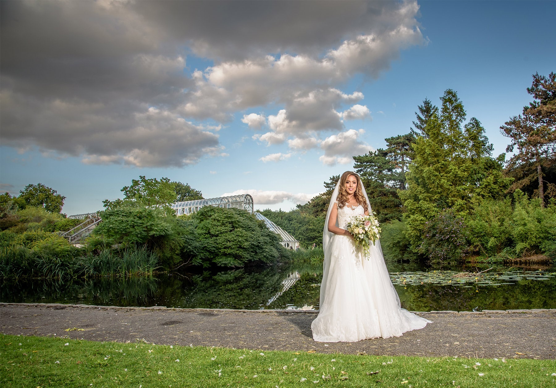 Bride with her bouquet by the pond in front of the Palm House at Kew Gardens