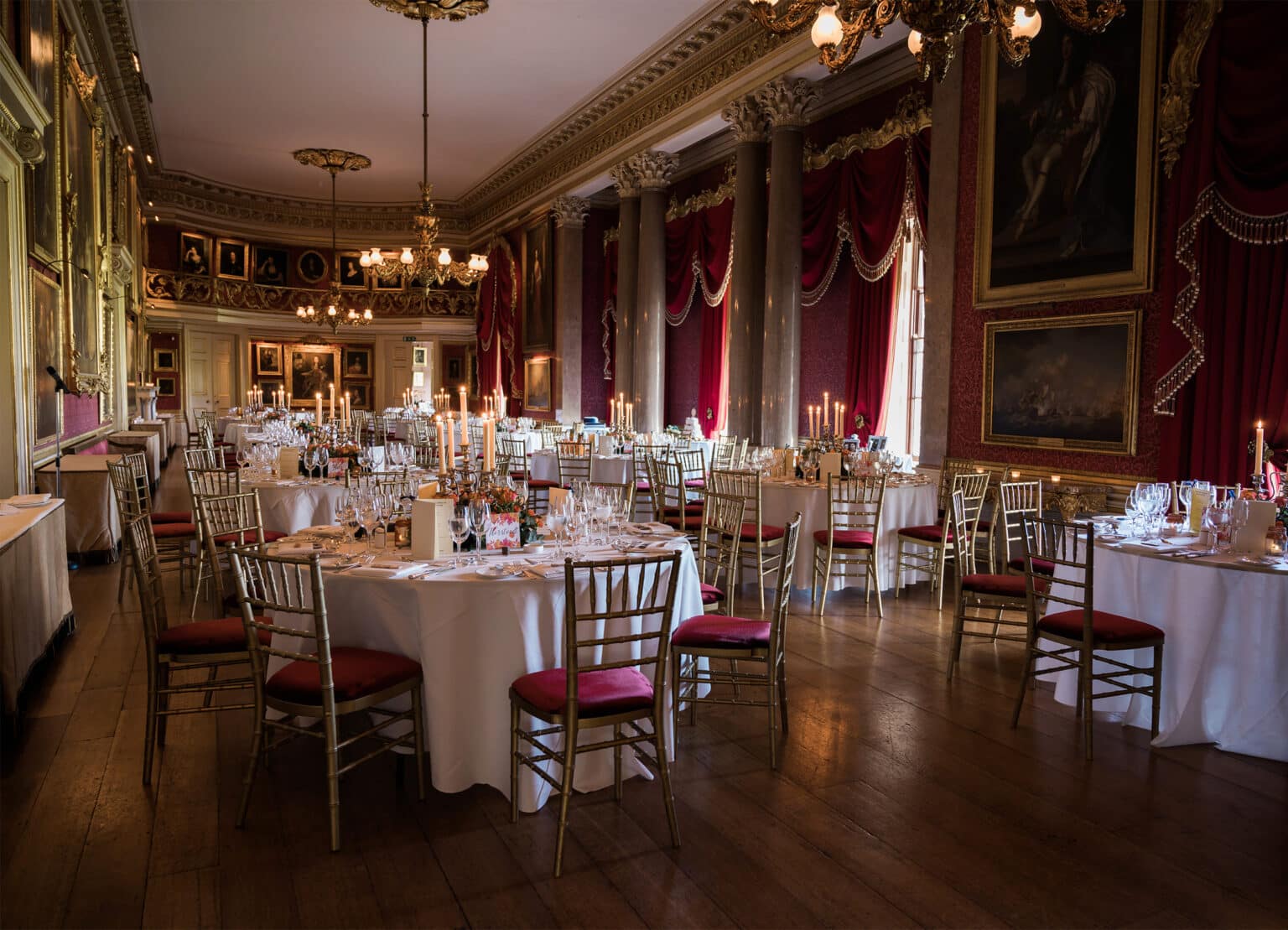 Tables set for a wedding dinner in the state rooms at Goodwood House