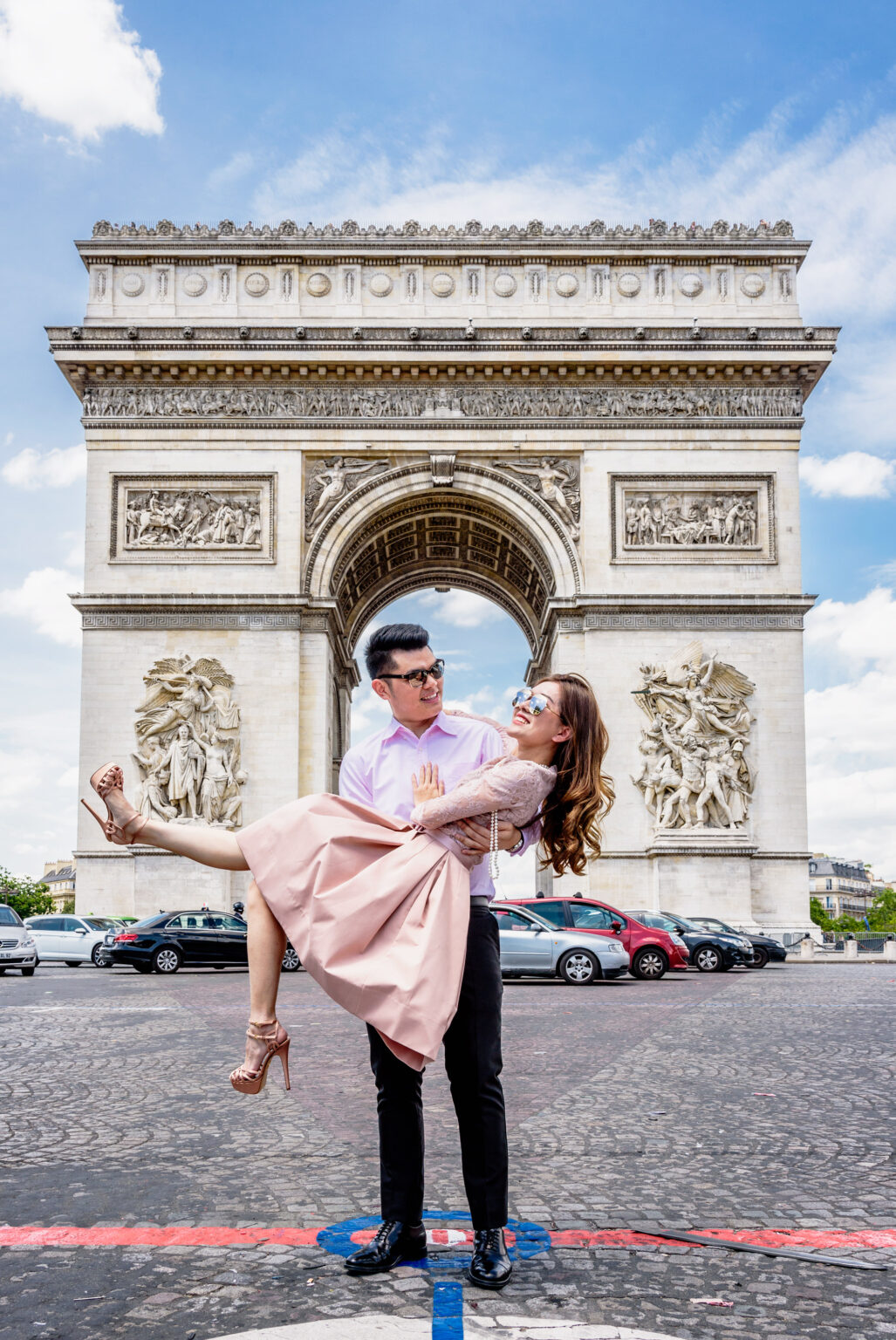 Groom lifting the bride in front of the Arc de Triomphe, Paris