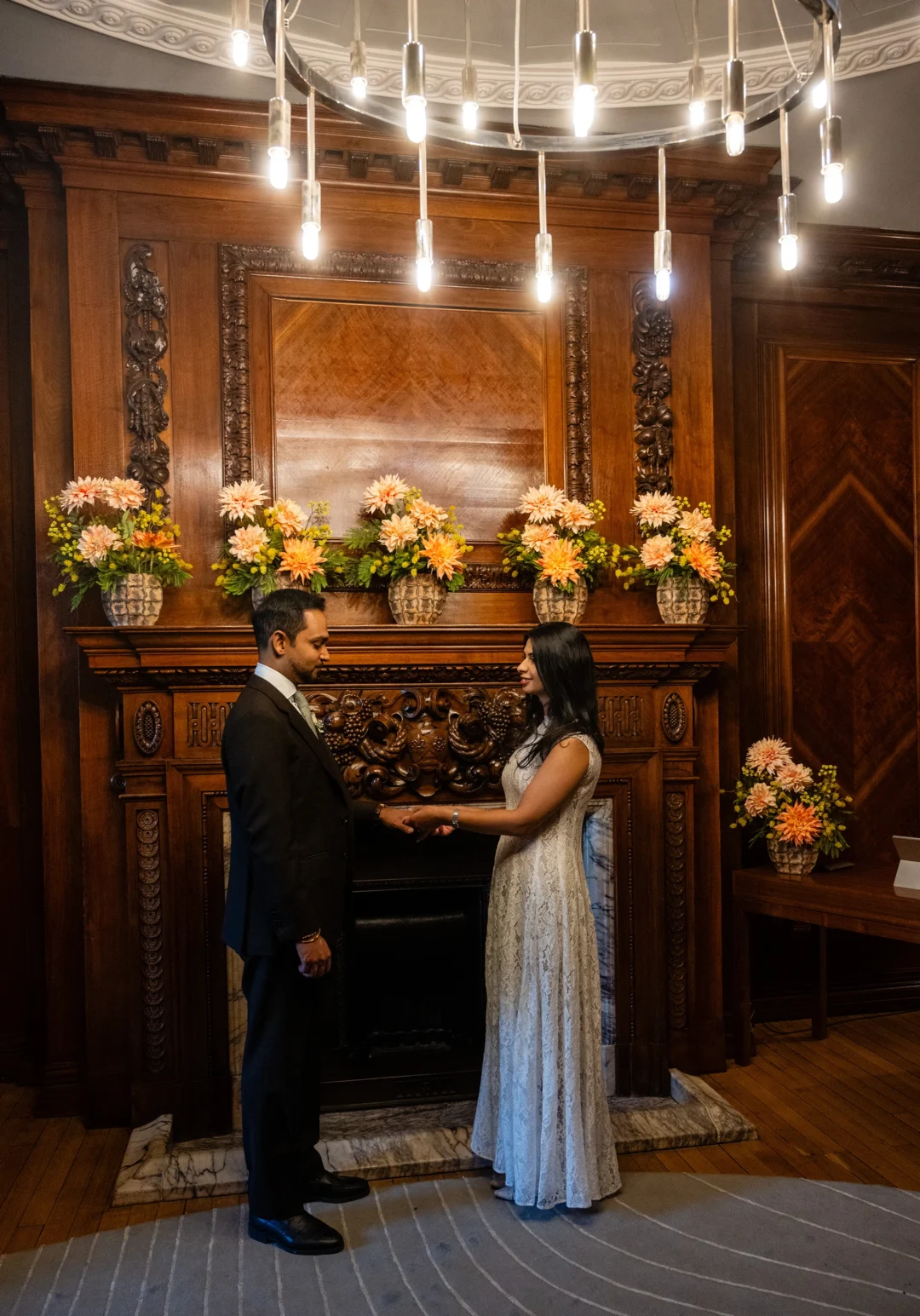 Bride and groom holding hands during their ceremony in a wood-panelled room at Marylebone