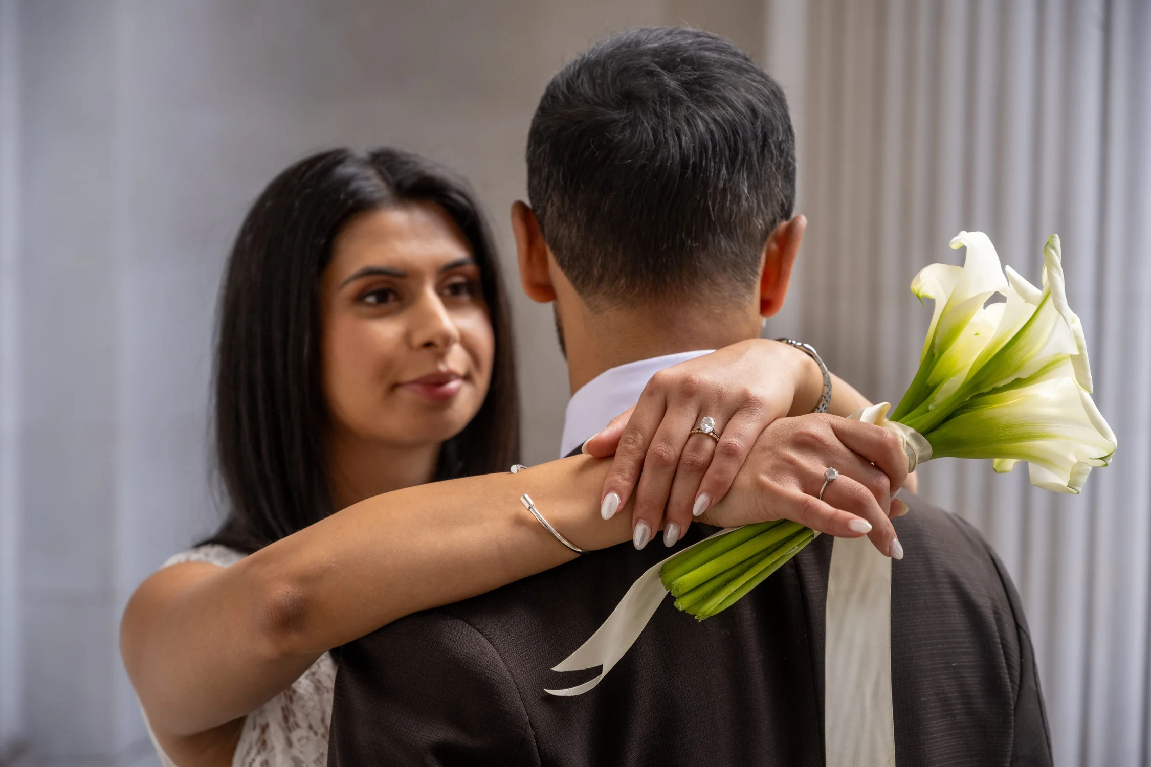 Bride holding calla lilies as she hugs the groom