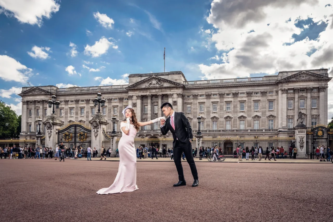 Groom kissing the bride's hand in front of Buckingham Palace, London pre wedding shoot