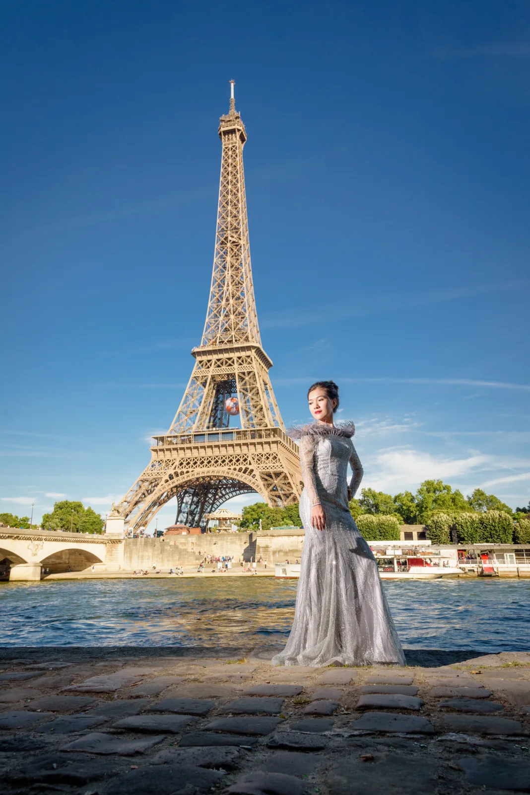 Bride in a grey gown by the Seine with the Eiffel Tower behind her