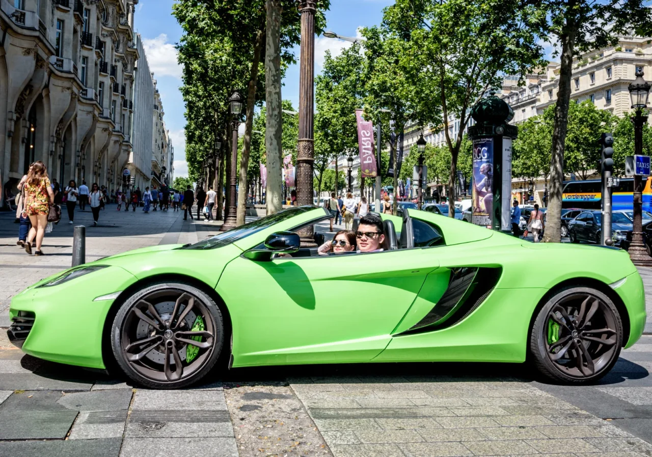 Couple in a green McLaren convertible on a tree-lined Paris avenue