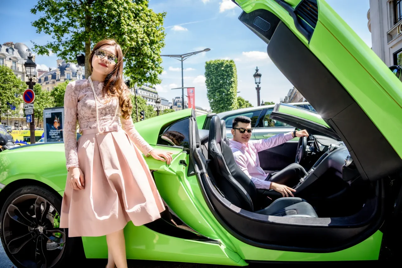 Bride in a pink dress beside a green McLaren with the groom at the wheel, Paris