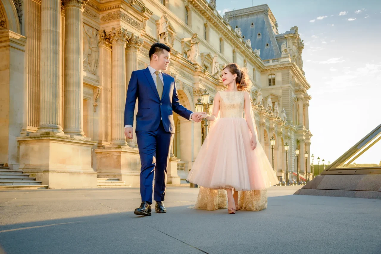 Groom leading the bride in a pink tulle gown along the Louvre, Paris