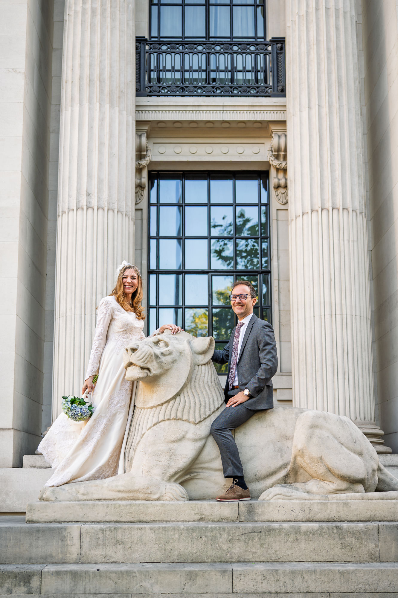 Bride and groom on the stone lion outside Old Marylebone Town Hall