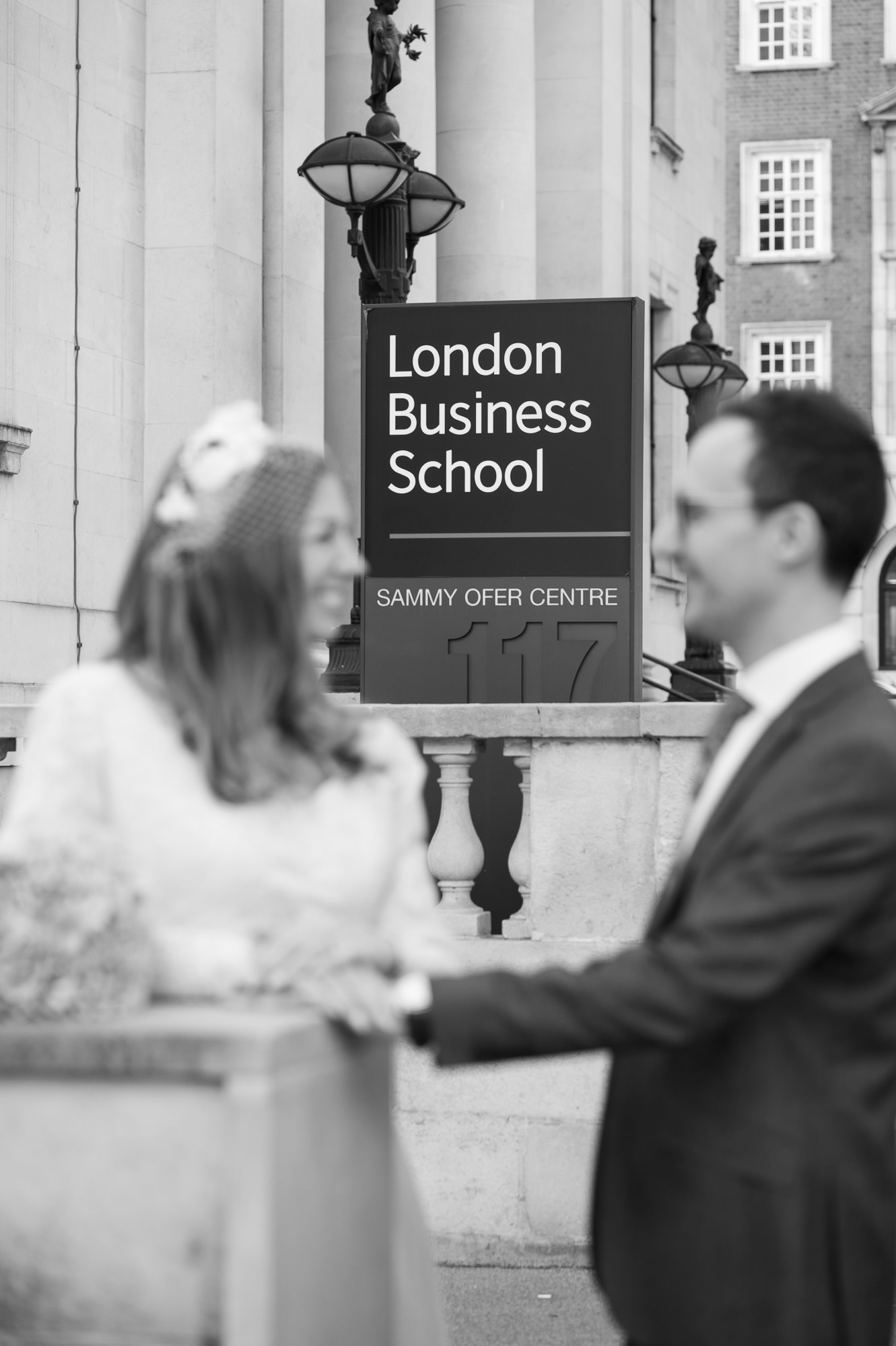 Bride and groom by the London Business School sign next to Old Marylebone Town Hall