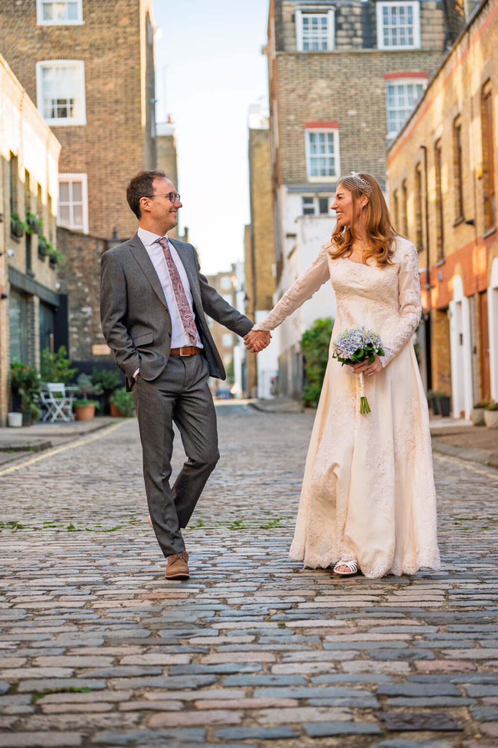 Bride and groom holding hands on a cobbled Marylebone mews after their Old Marylebone Town Hall wedding