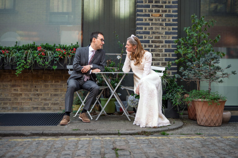 Bride and groom at a cafe table on a Marylebone mews after their Old Marylebone Town Hall wedding