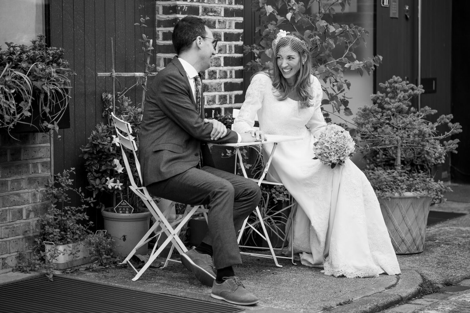 Black and white photo of the bride and groom at a cafe table on a Marylebone mews