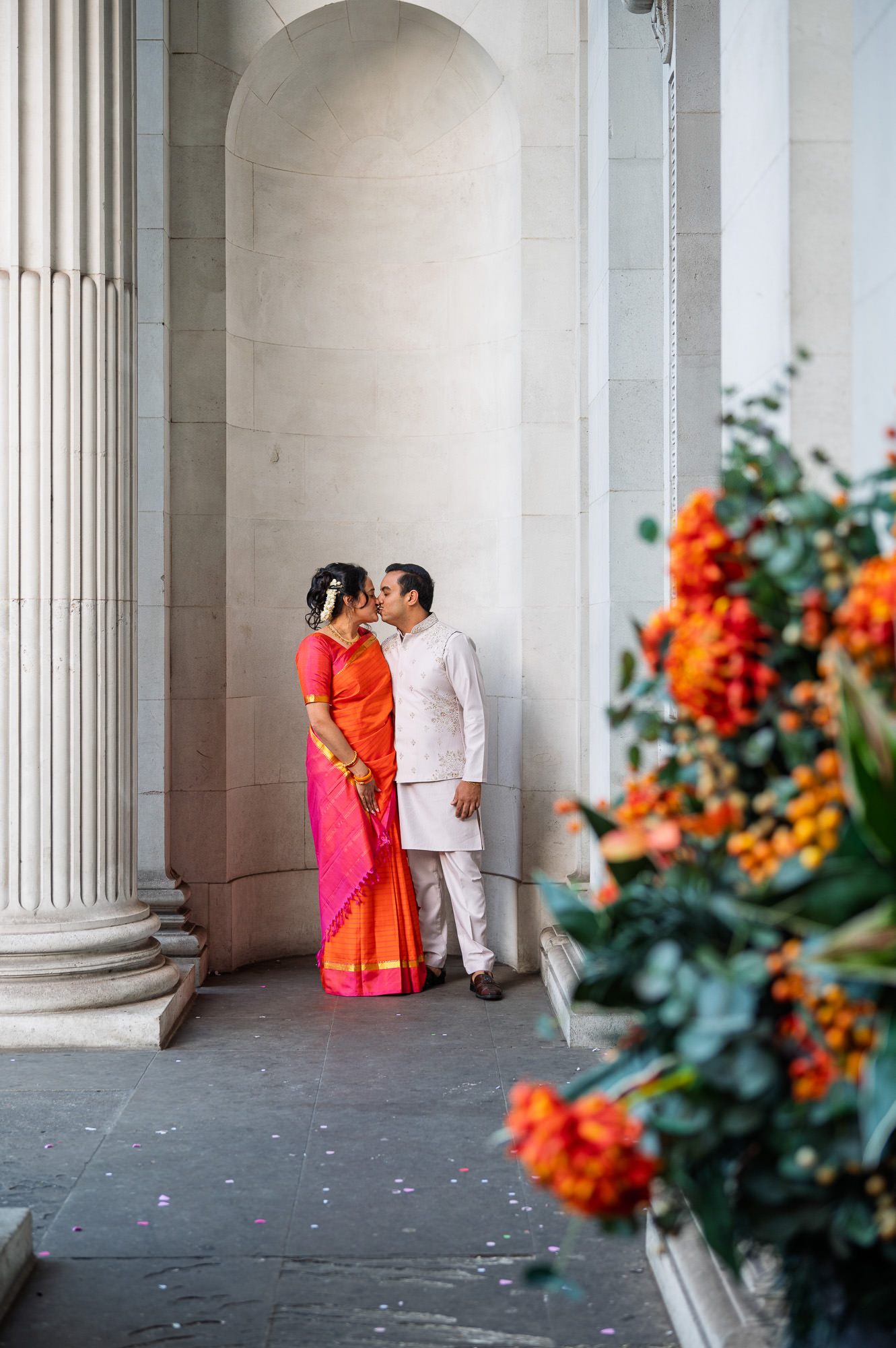 Bride and groom kissing between the columns at Old Marylebone Town Hall