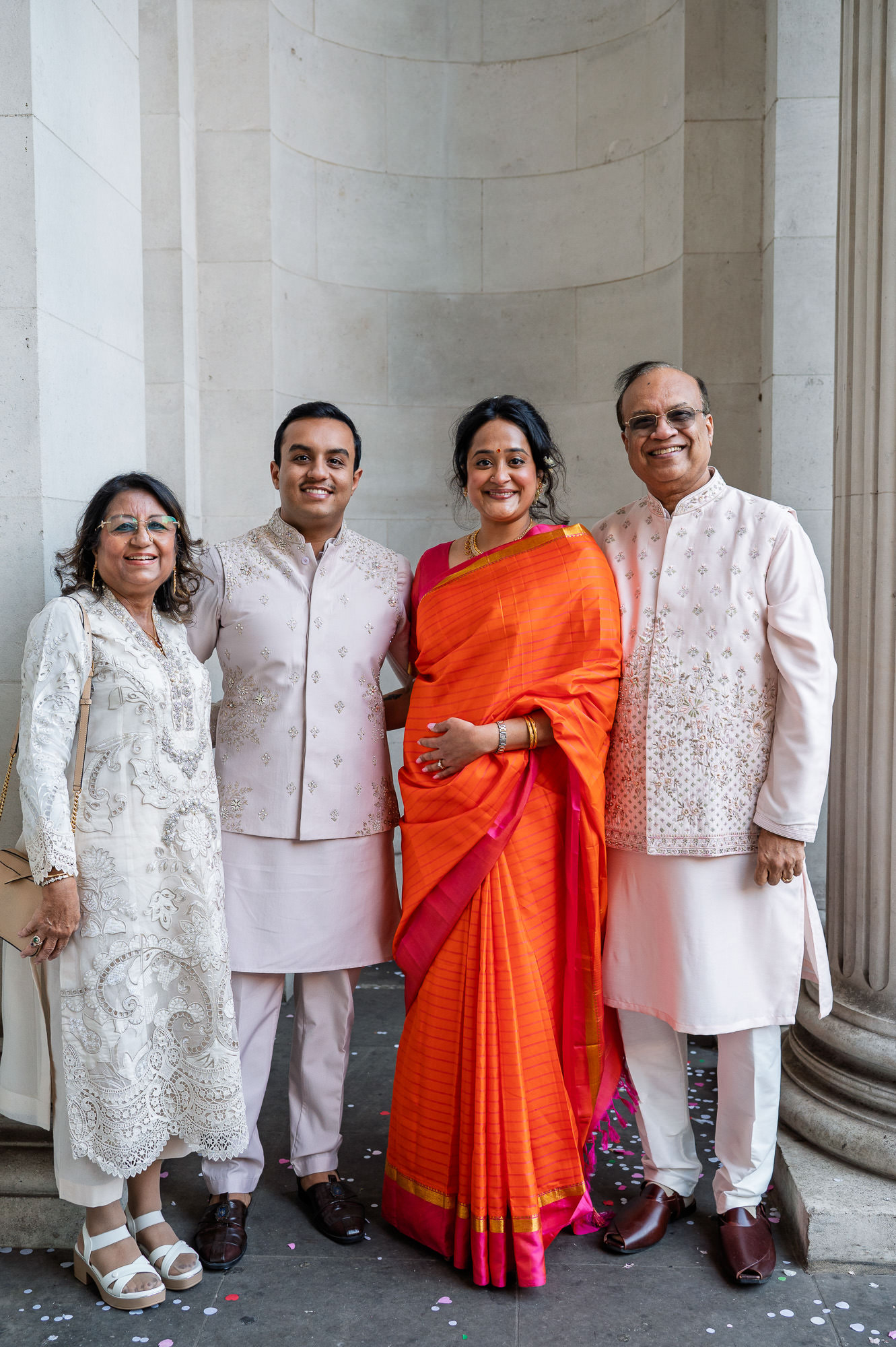 Bride and groom with family between the stone columns at Old Marylebone Town Hall