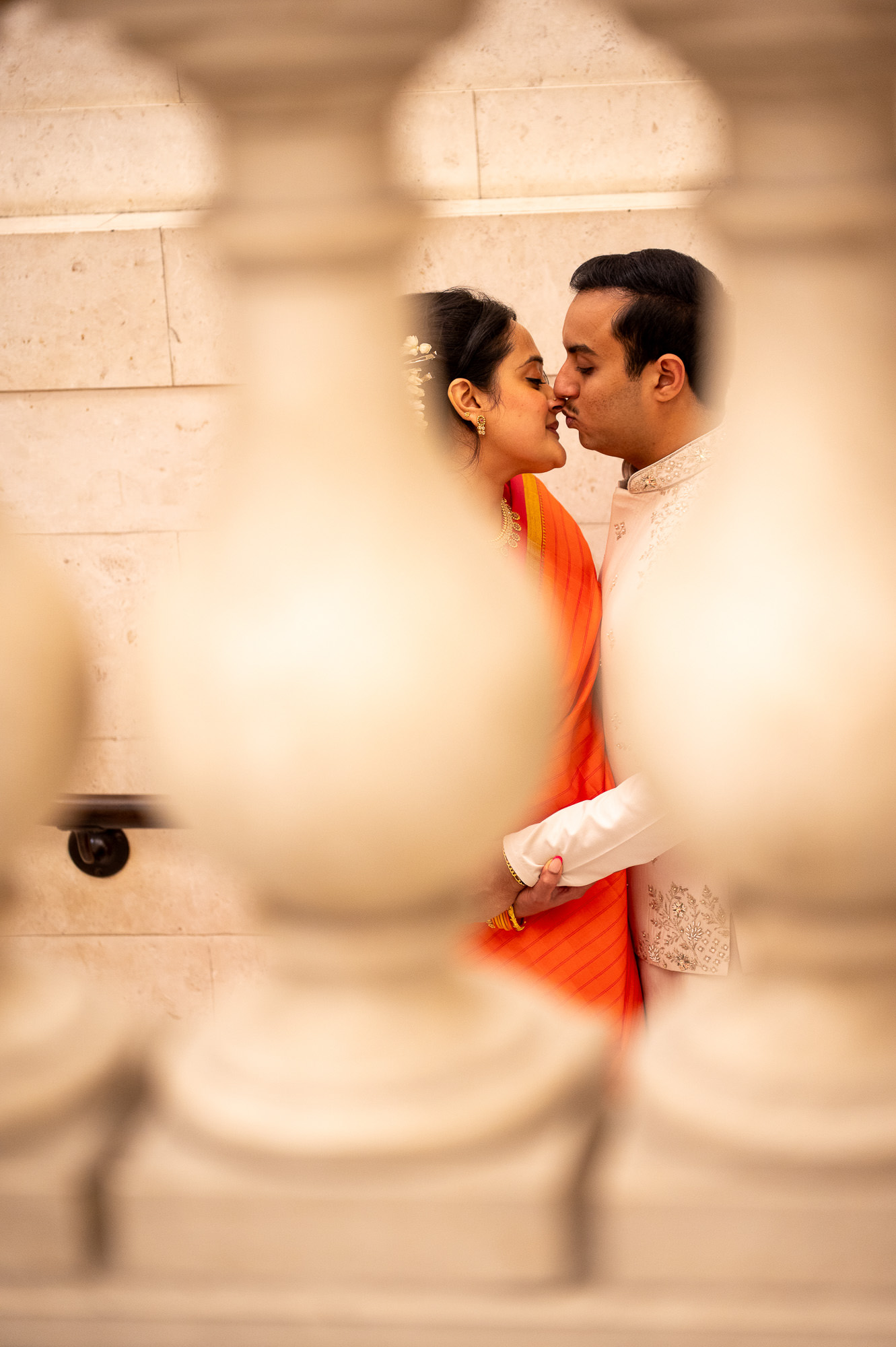 Bride and groom framed through a stone balustrade at Old Marylebone Town Hall