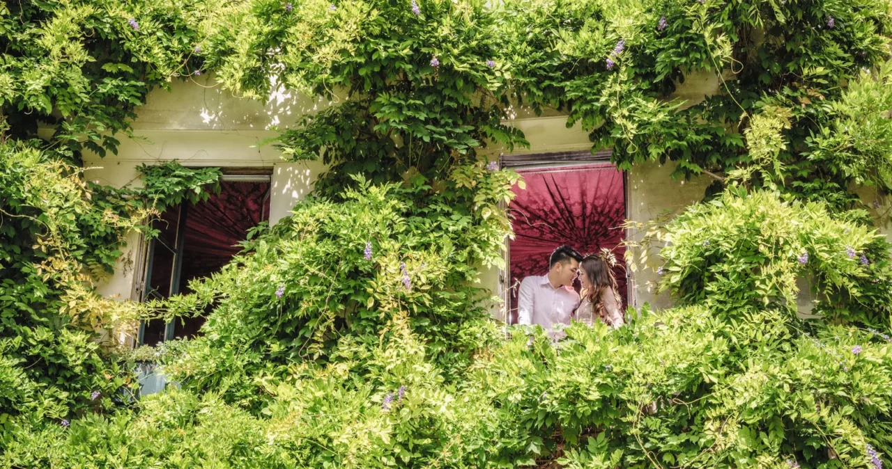 Couple framed in a window surrounded by greenery at a Paris cafe