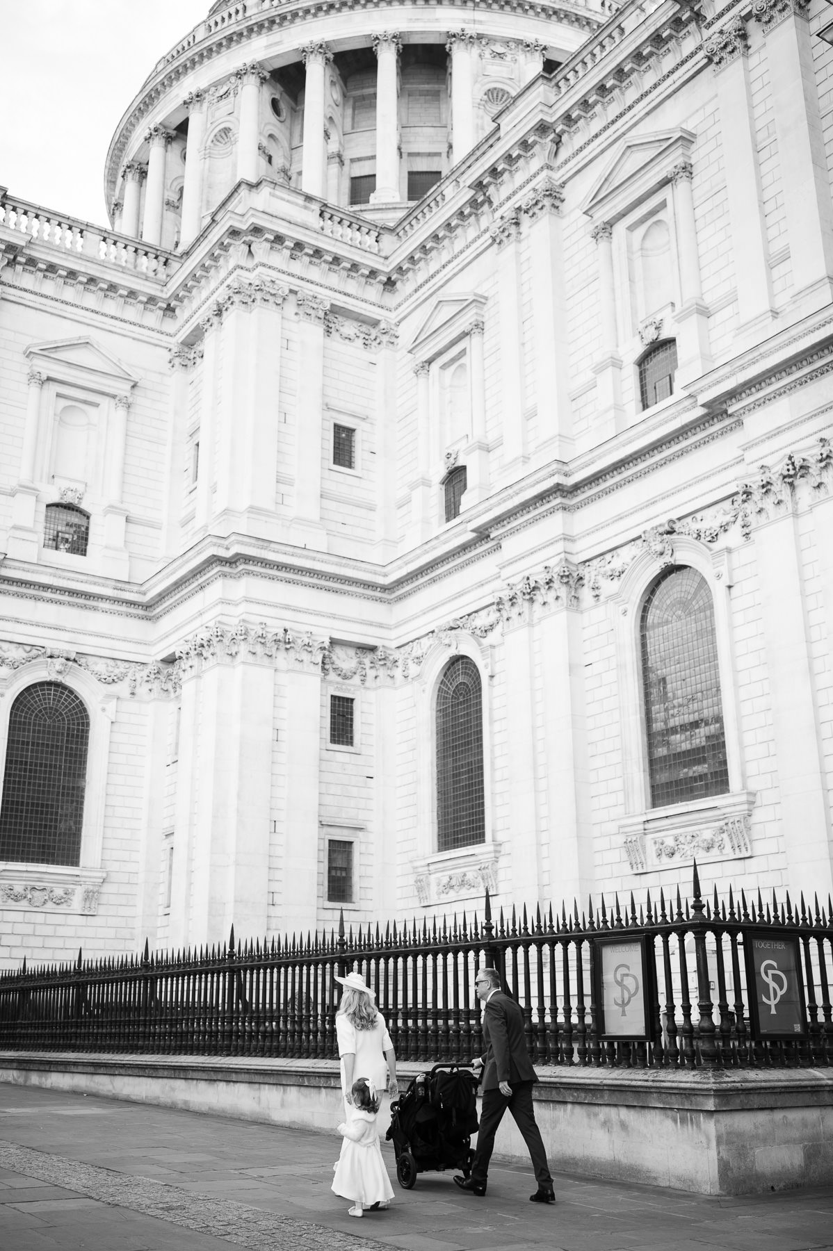 Black and white photo of the family walking beside the railings at St Paul's Cathedral with the pram