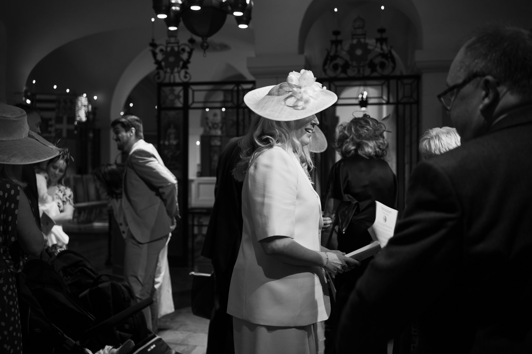 Black and white photo of guests greeting each other in the OBE Chapel before the christening