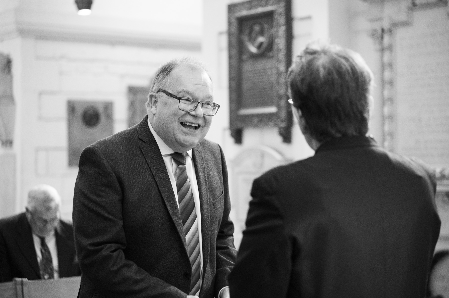 Black and white photo of a guest laughing before the christening at St Paul's Cathedral
