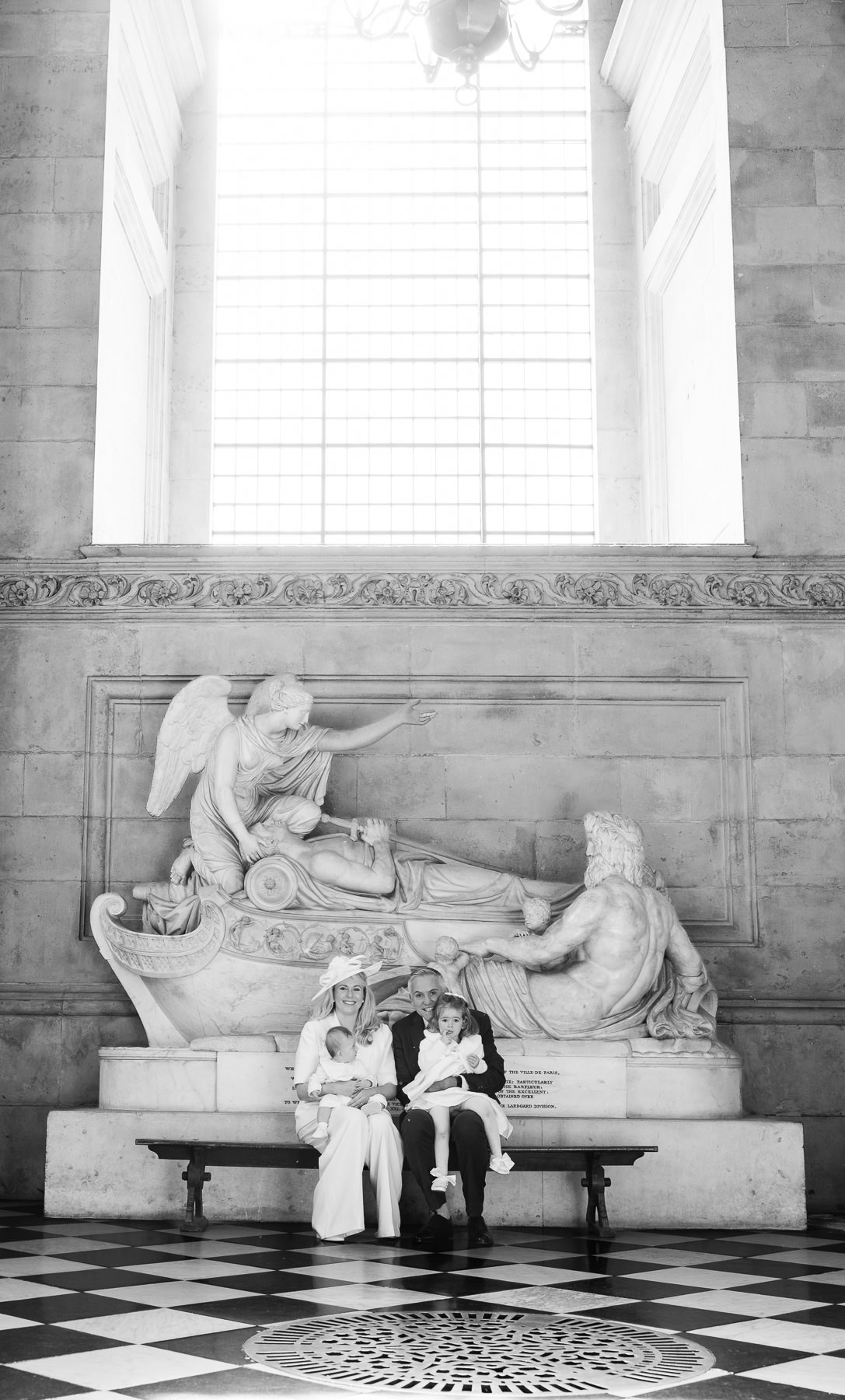 Black and white photo of the family on a bench beneath a marble monument in St Paul's Cathedral