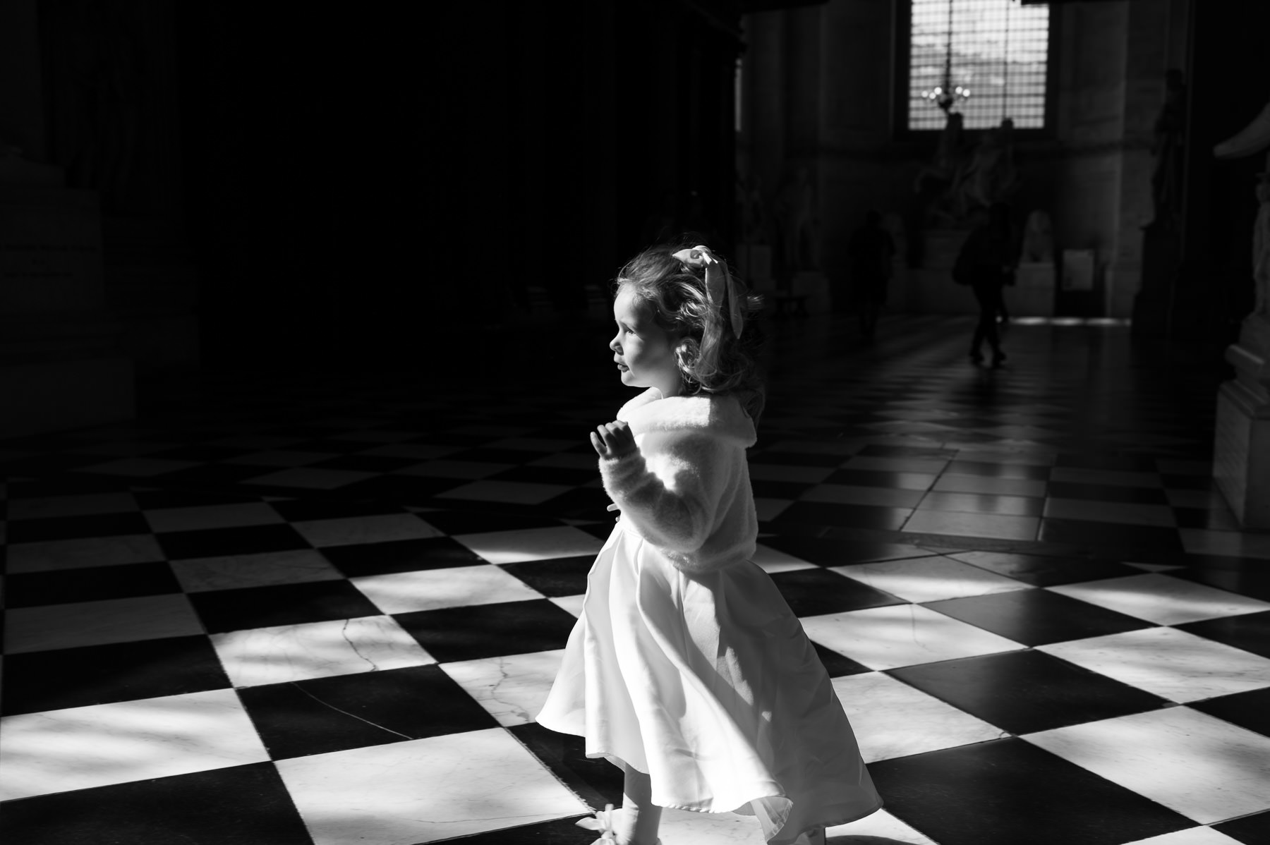 Little girl in a white dress walking across the black and white marble floor at St Paul's Cathedral