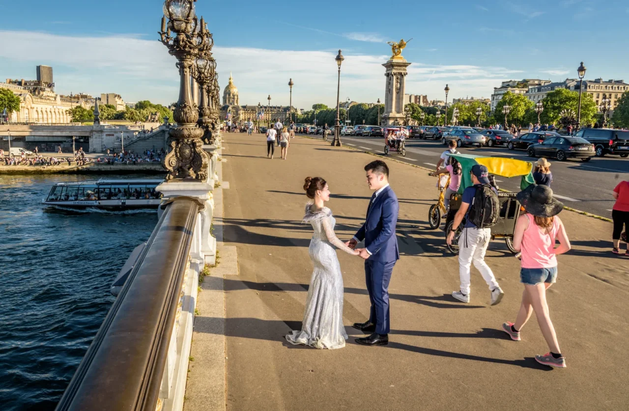Bride and groom holding hands on Pont Alexandre III with its gilded lamps