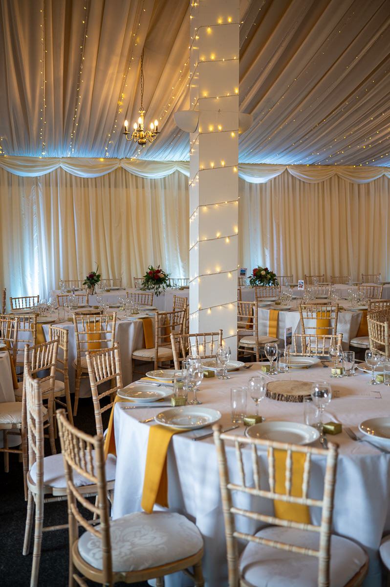 The barn at Selden Barns set for the wedding breakfast, tables laid under fairy lights