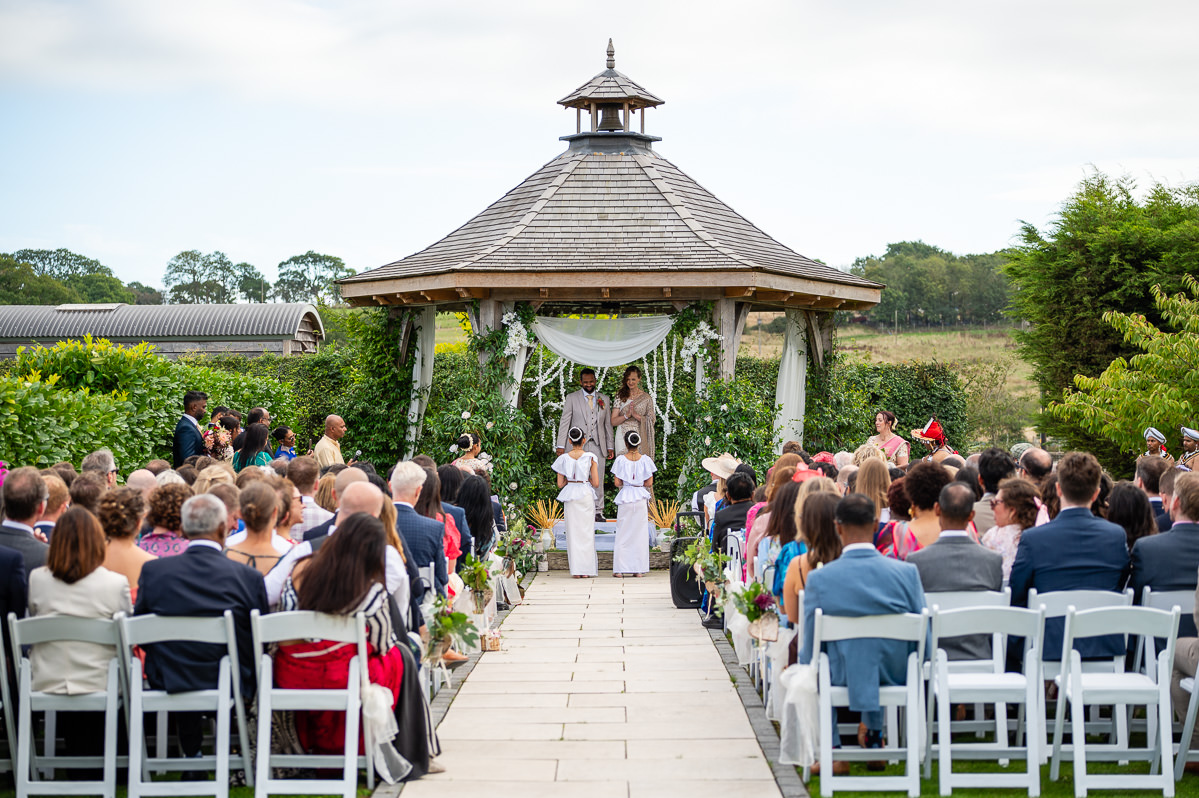 Guests seated for the ceremony at the oak pergola, Selden Barns, West Sussex