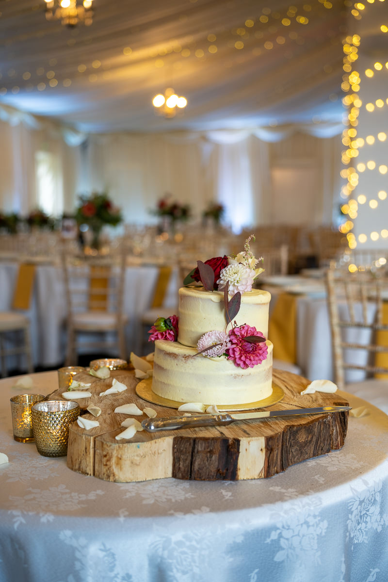The wedding cake on a wooden slice in the barn at Selden Barns