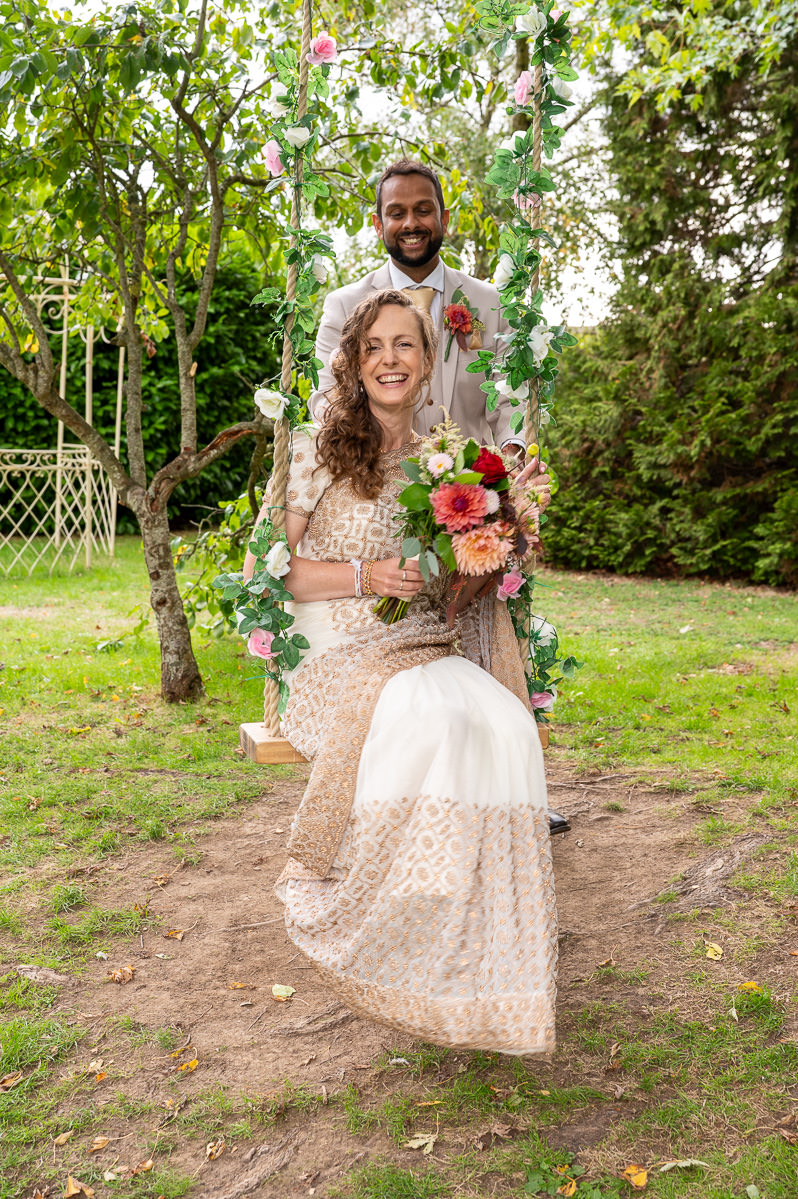 The bride and groom on the flower swing in the garden at Selden Barns