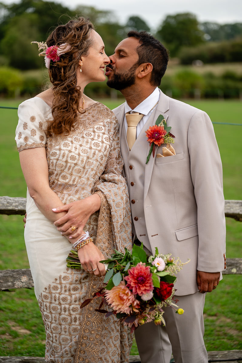 The groom kissing the bride by the paddock fence at Selden Barns