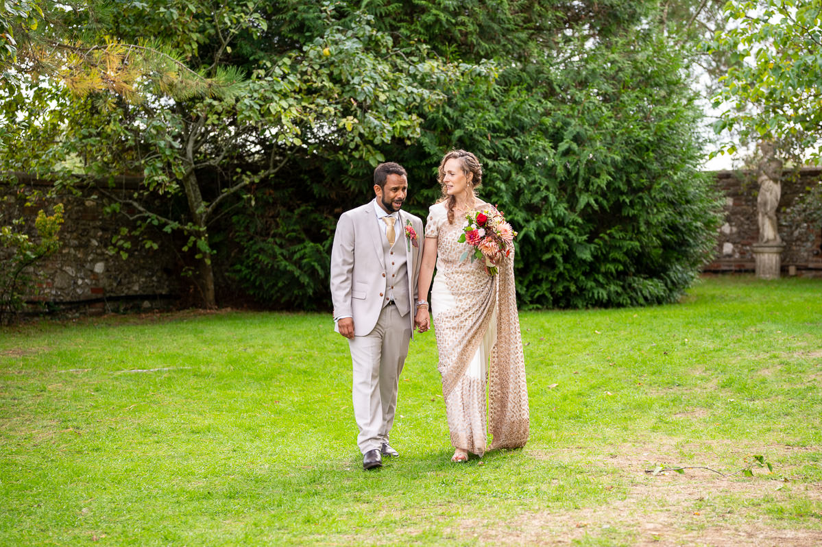 The bride and groom walking across the lawn at Selden Barns