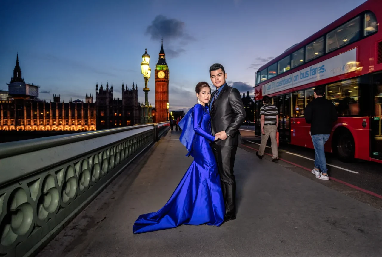 Bride in royal blue gown and groom on Westminster Bridge at night with Big Ben and a red bus