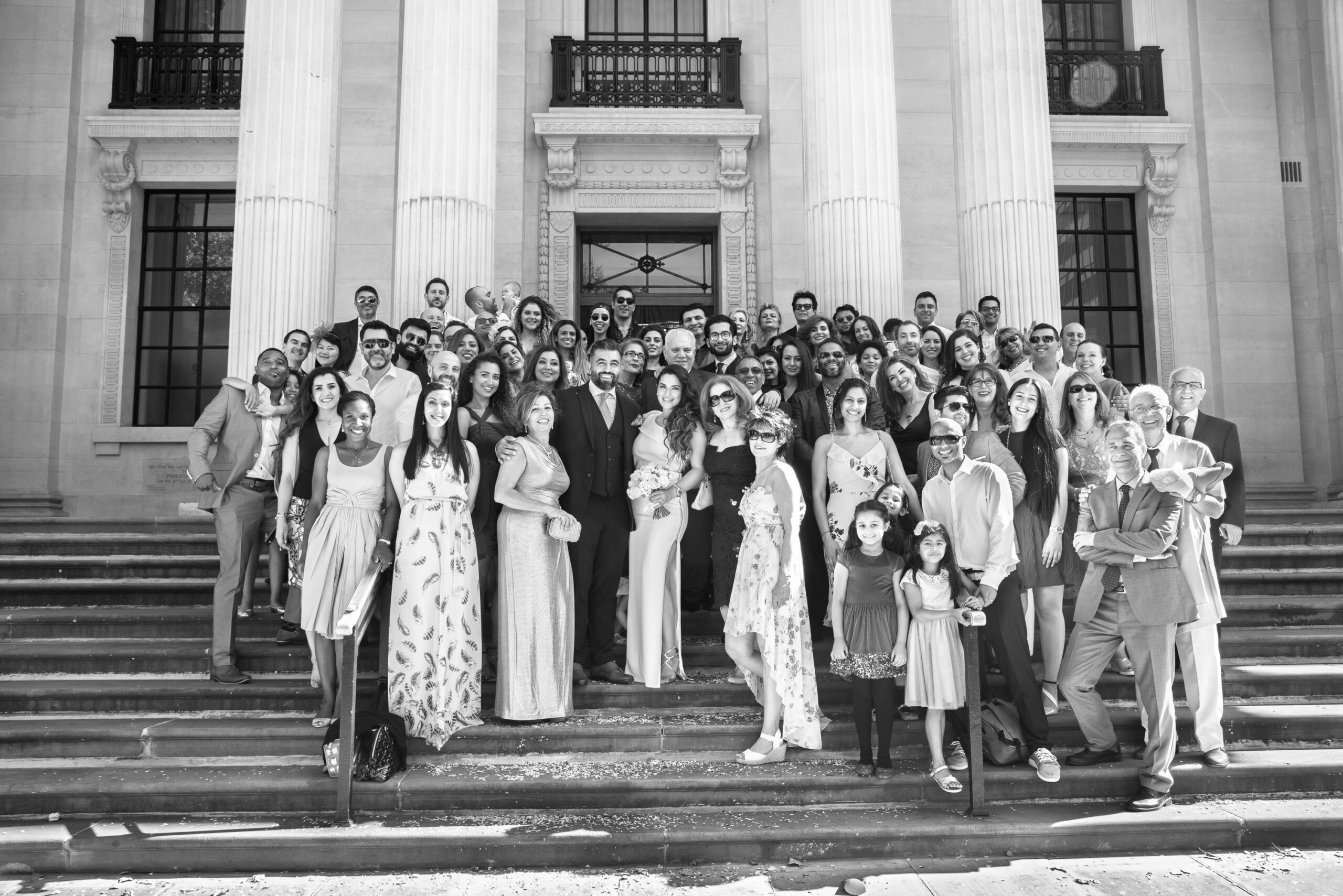 Black and white photo of the whole wedding party on the front steps of Old Marylebone Town Hall