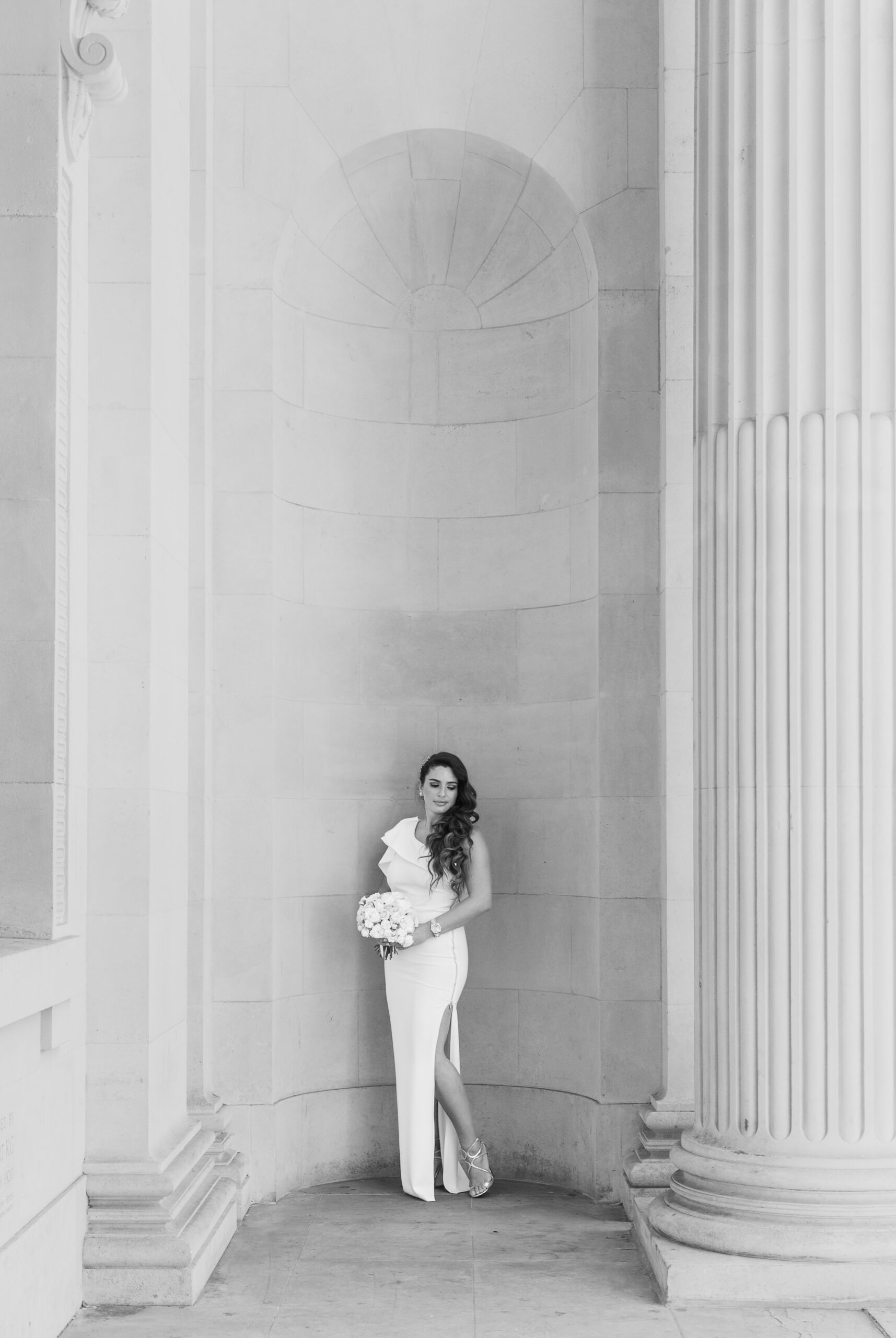 Black and white photo of Bibi standing in a stone niche between the columns at Old Marylebone Town Hall