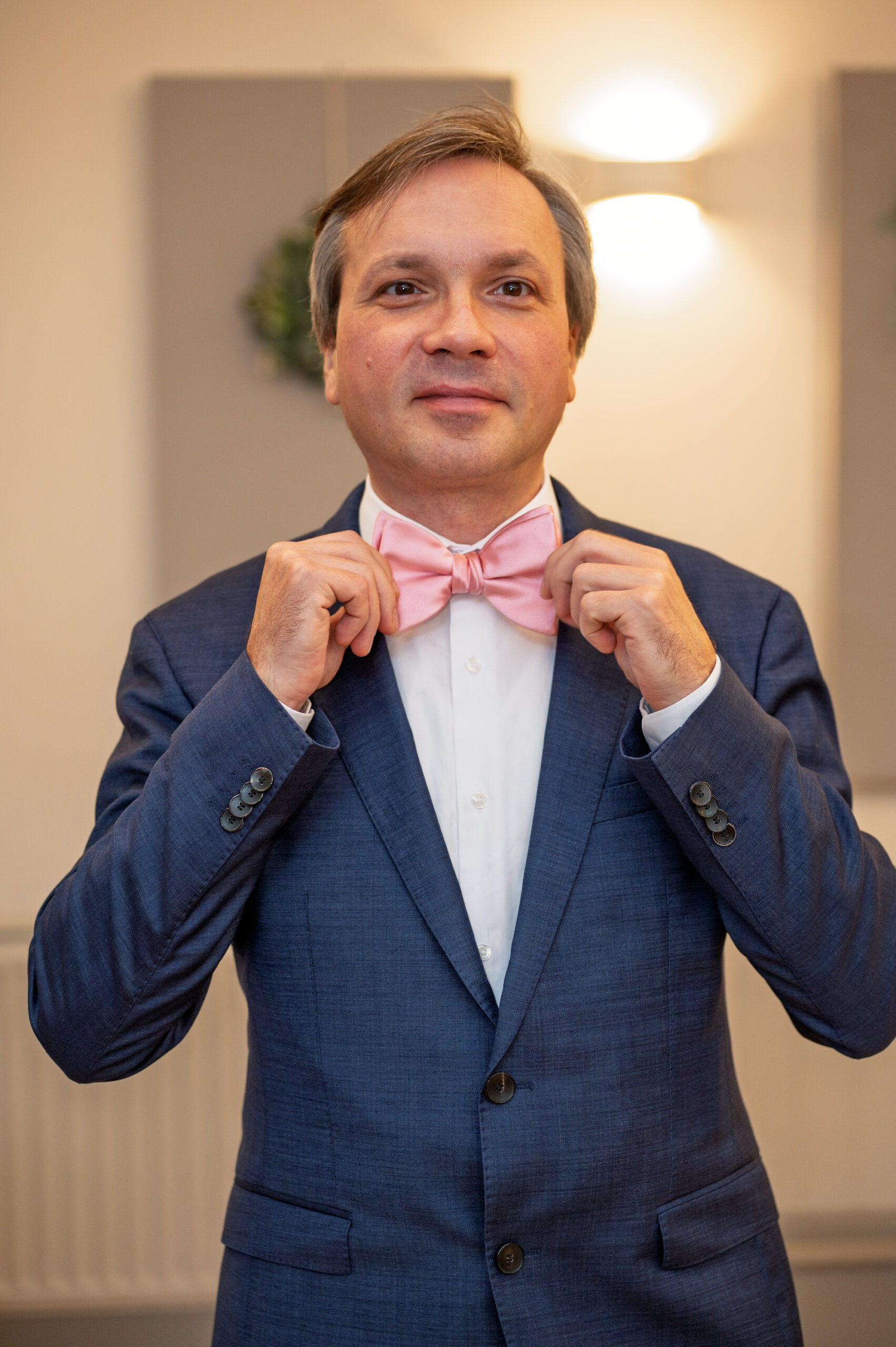 Alexei adjusting his pink bow tie before his wedding ceremony in Ealing, London
