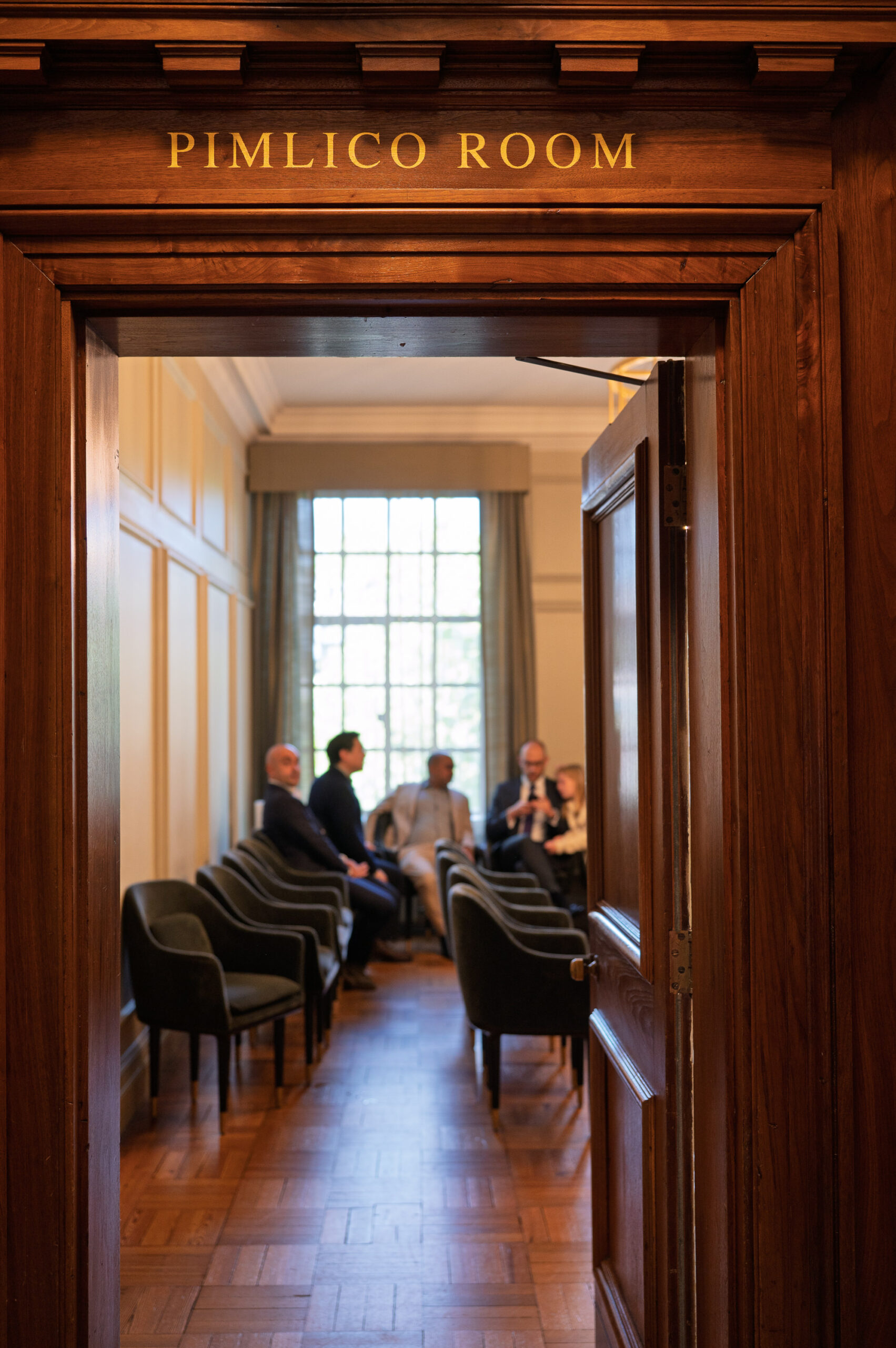 Guests seated in the Pimlico Room at Old Marylebone Town Hall, seen through the doorway under the room's gold lettering