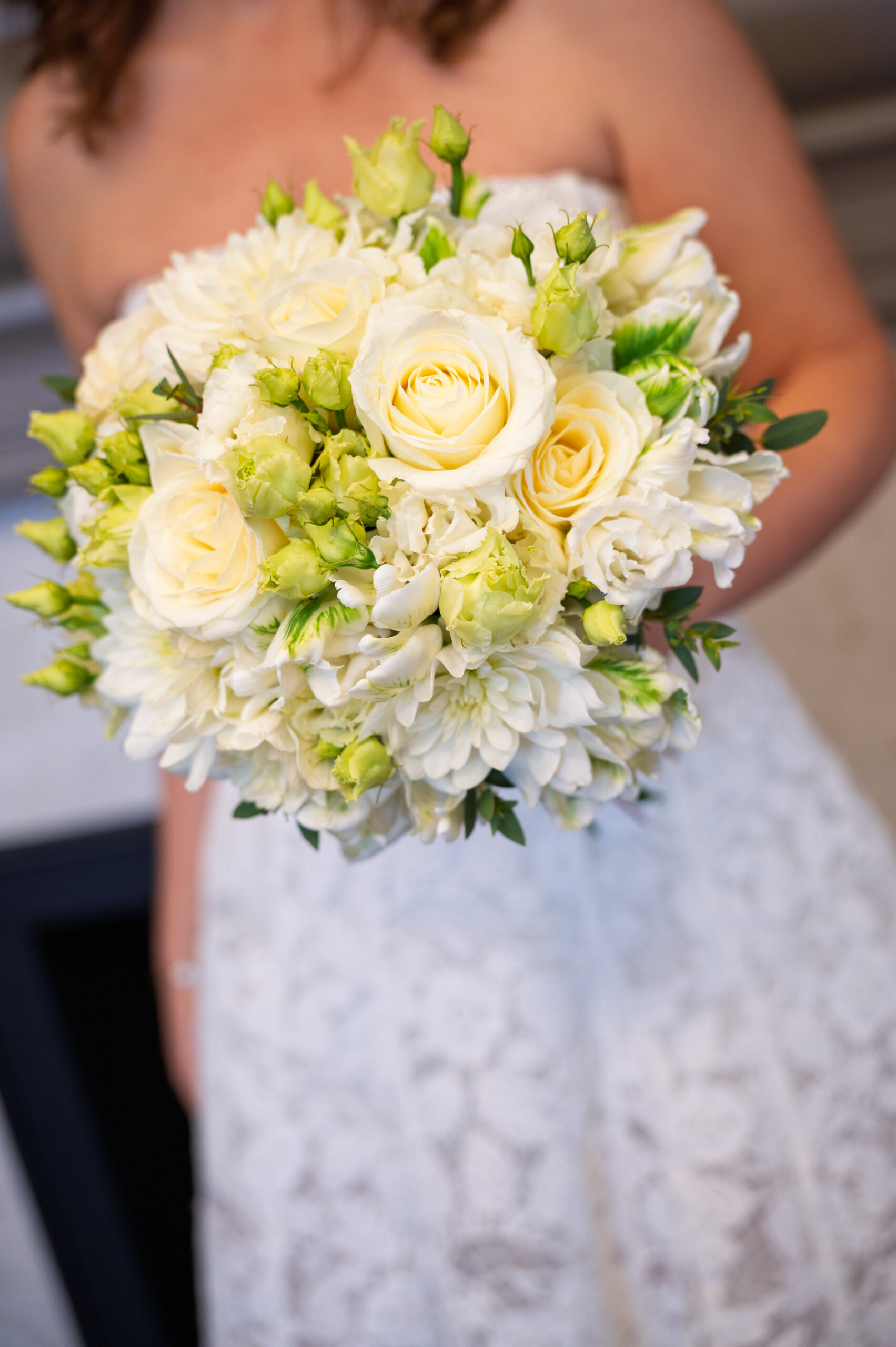 Close-up of the bride's ivory rose bouquet against her lace dress at Old Marylebone Town Hall
