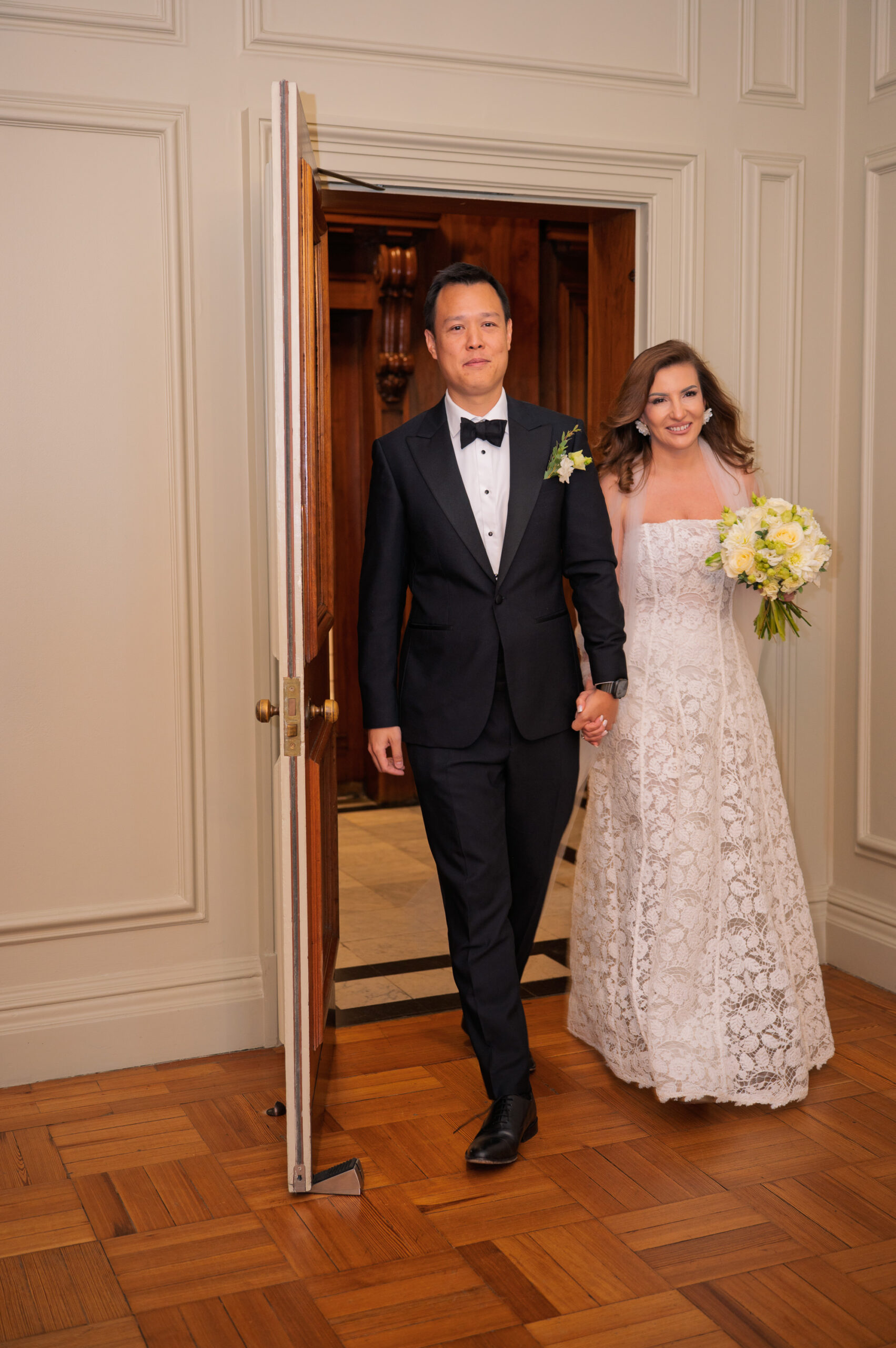 Nicoleta and Alistair walking through the doorway into the Pimlico Room at Old Marylebone Town Hall